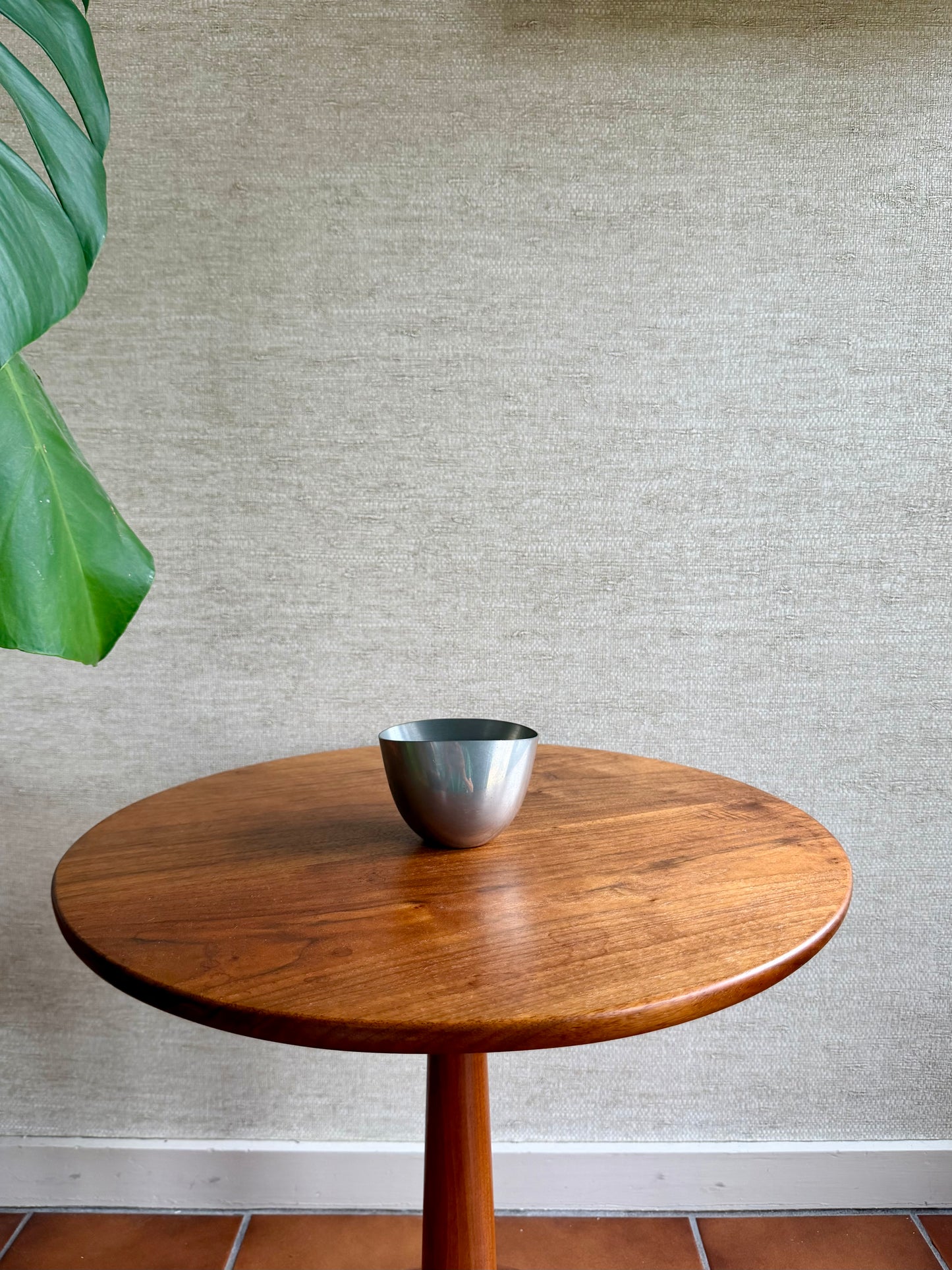 Wooden table with a silver bowl on a textured wall background