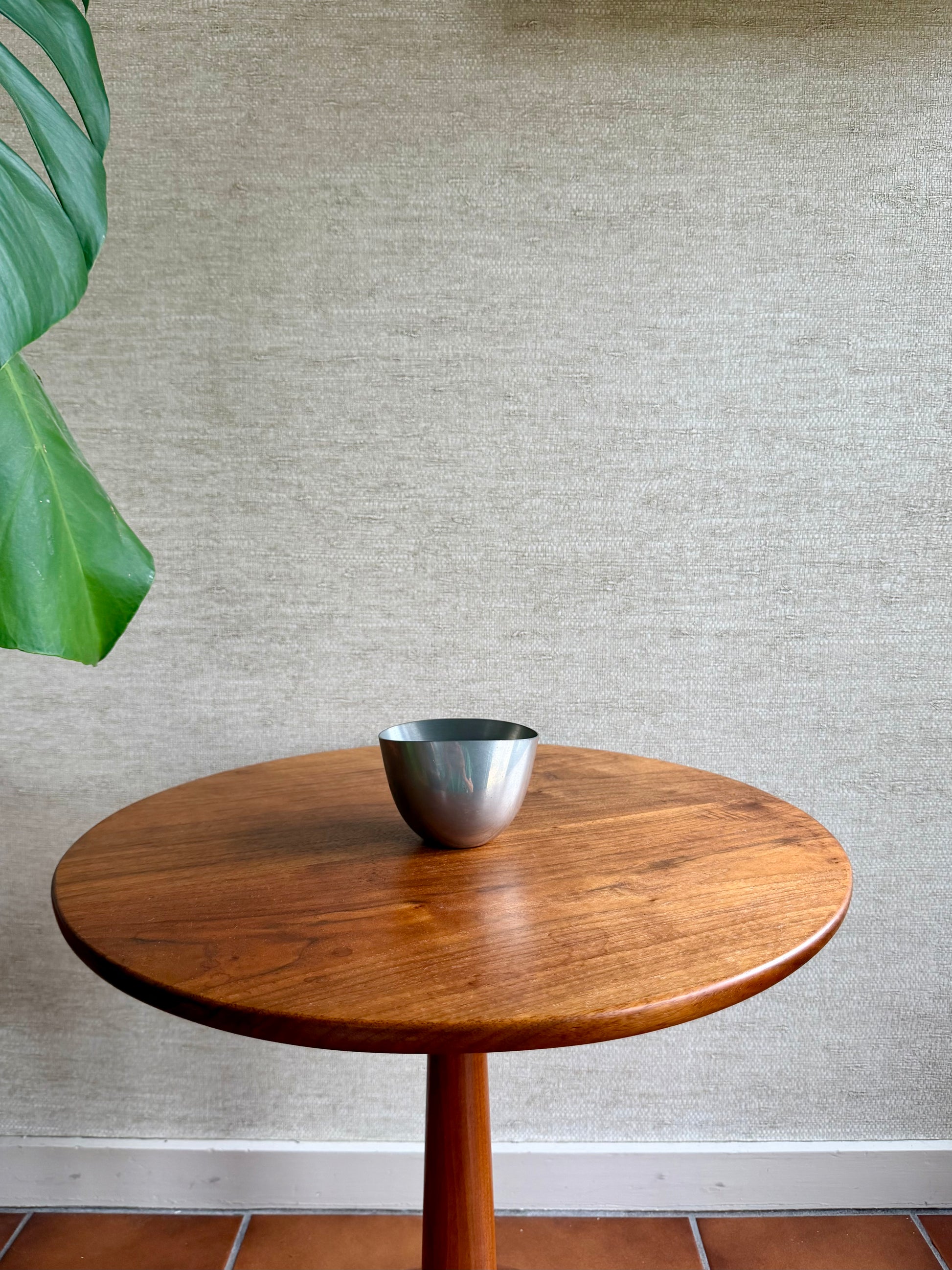 Wooden table with a silver bowl on a textured wall background