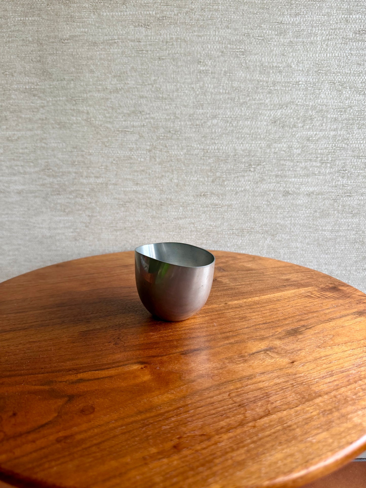 Silver bowl on a wooden table with a gray textured wall background