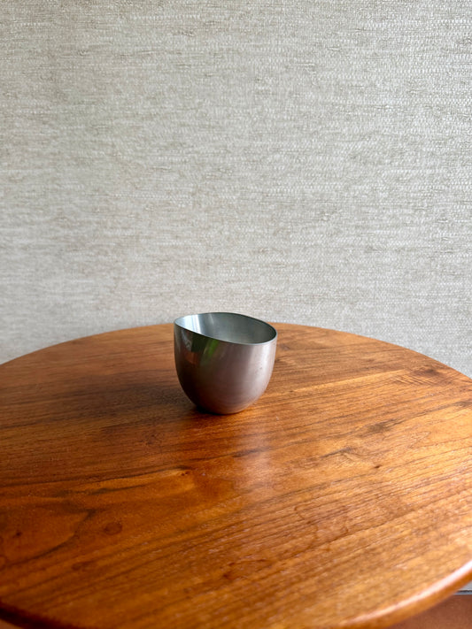 Silver bowl on a wooden table with a gray textured wall background