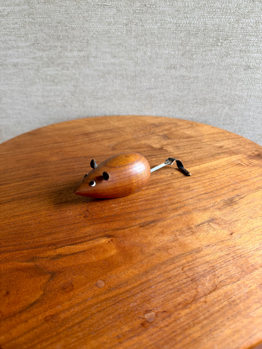 Wooden mouse-shaped toy on a wooden surface with a gray background
