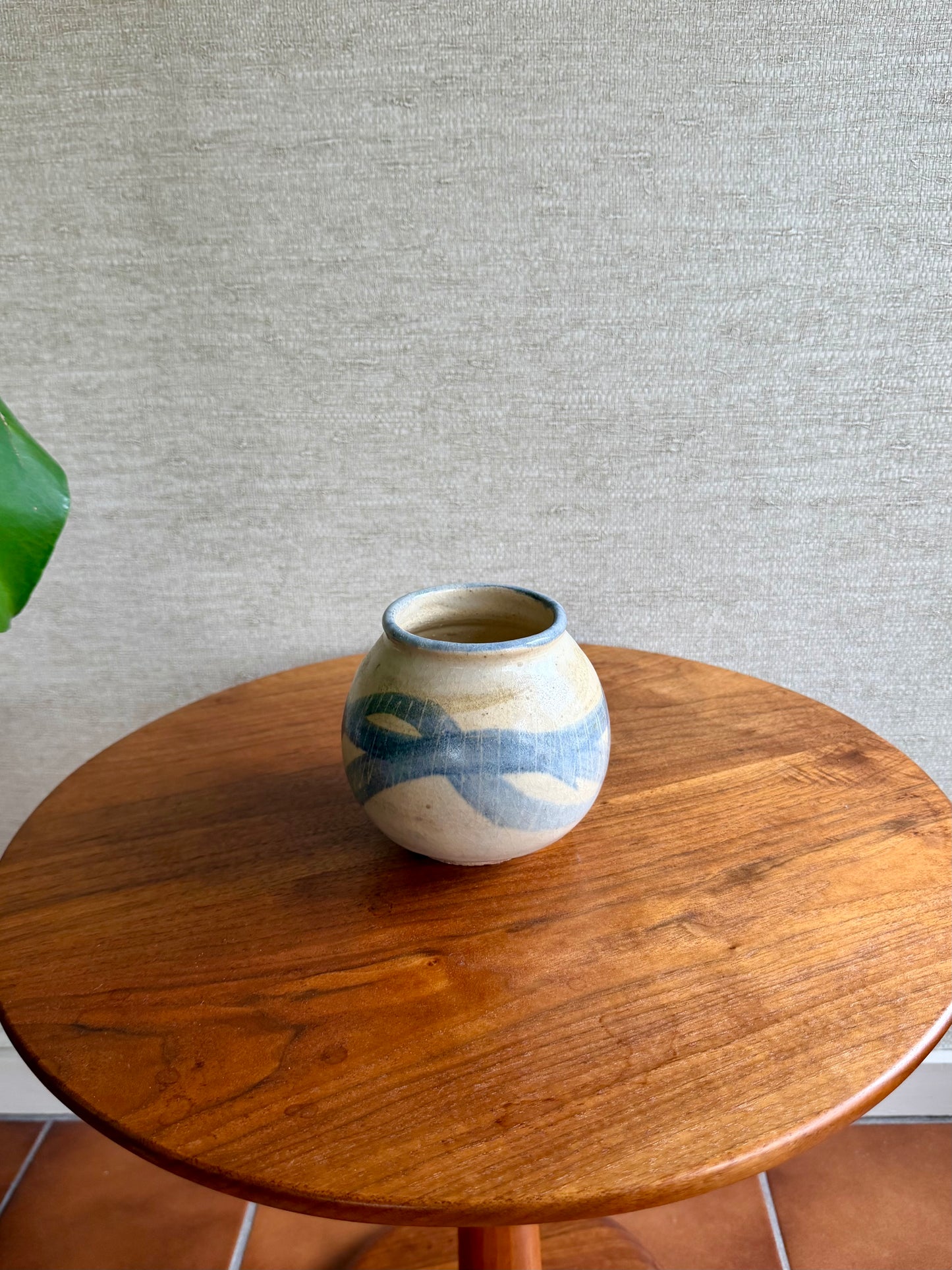 Ceramic vase with blue patterns on a wooden table against a gray wall