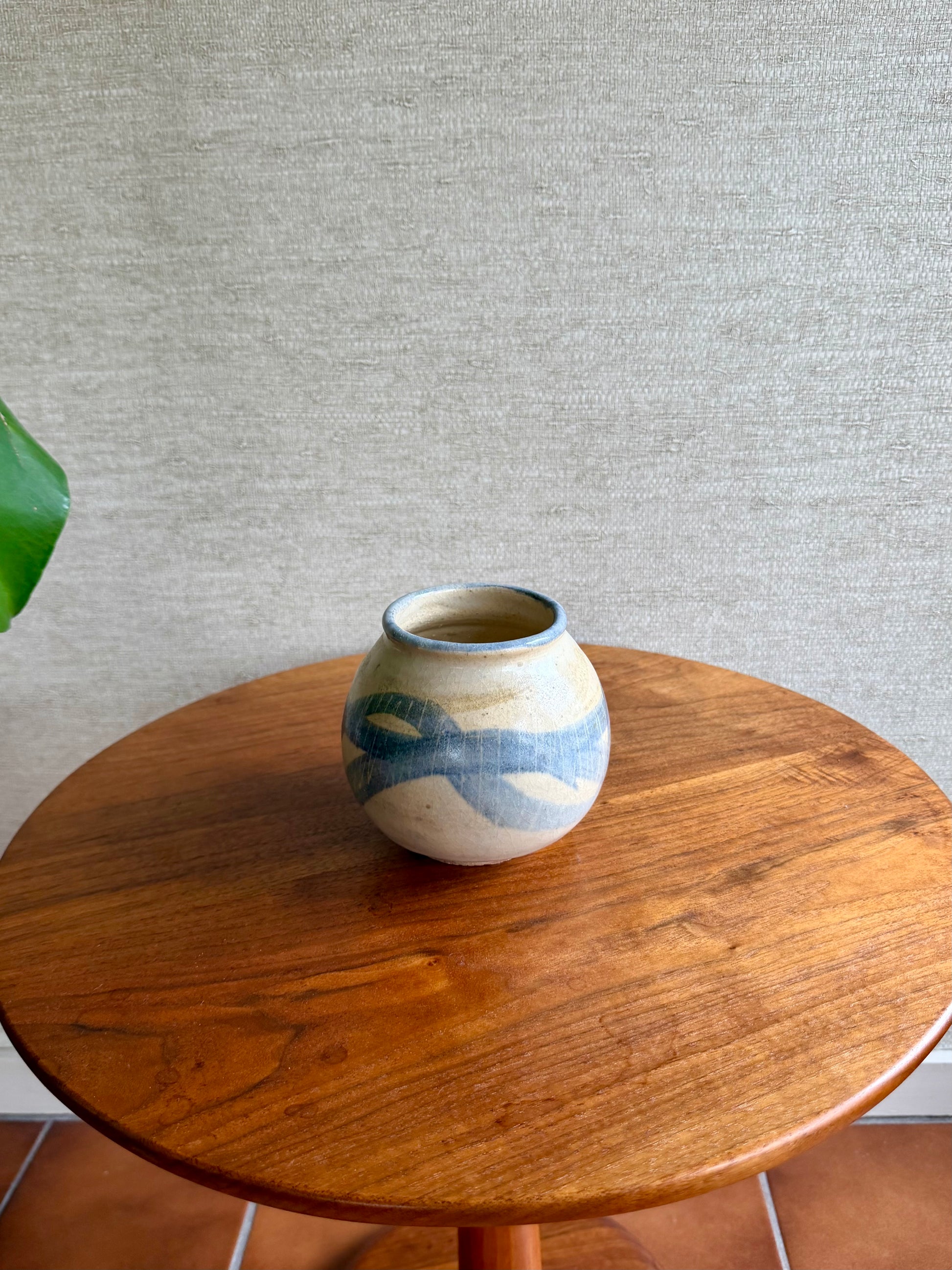 Ceramic vase with blue patterns on a wooden table against a gray wall