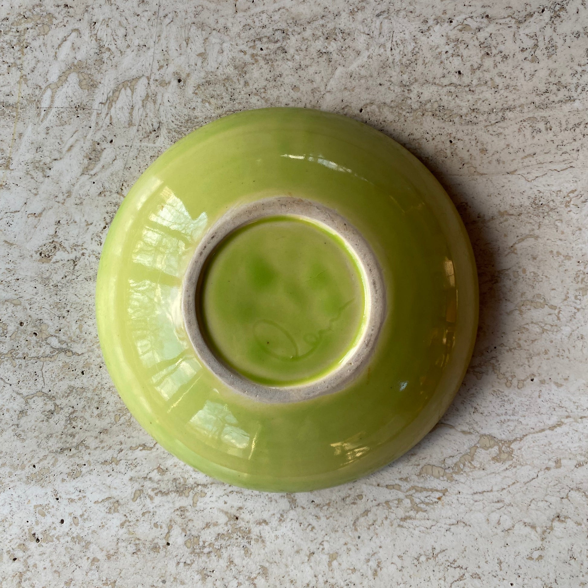 Green ceramic bowl on a textured stone surface