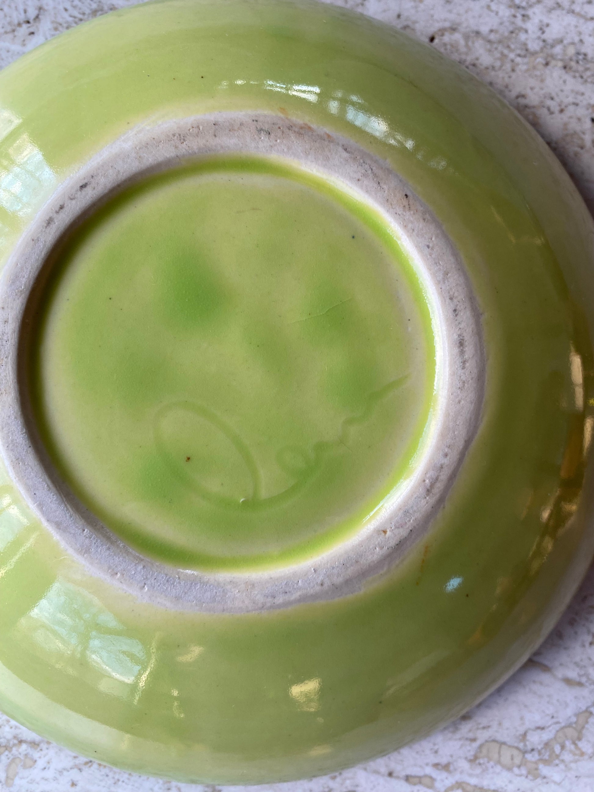 Green ceramic plate with a textured rim on a light surface
