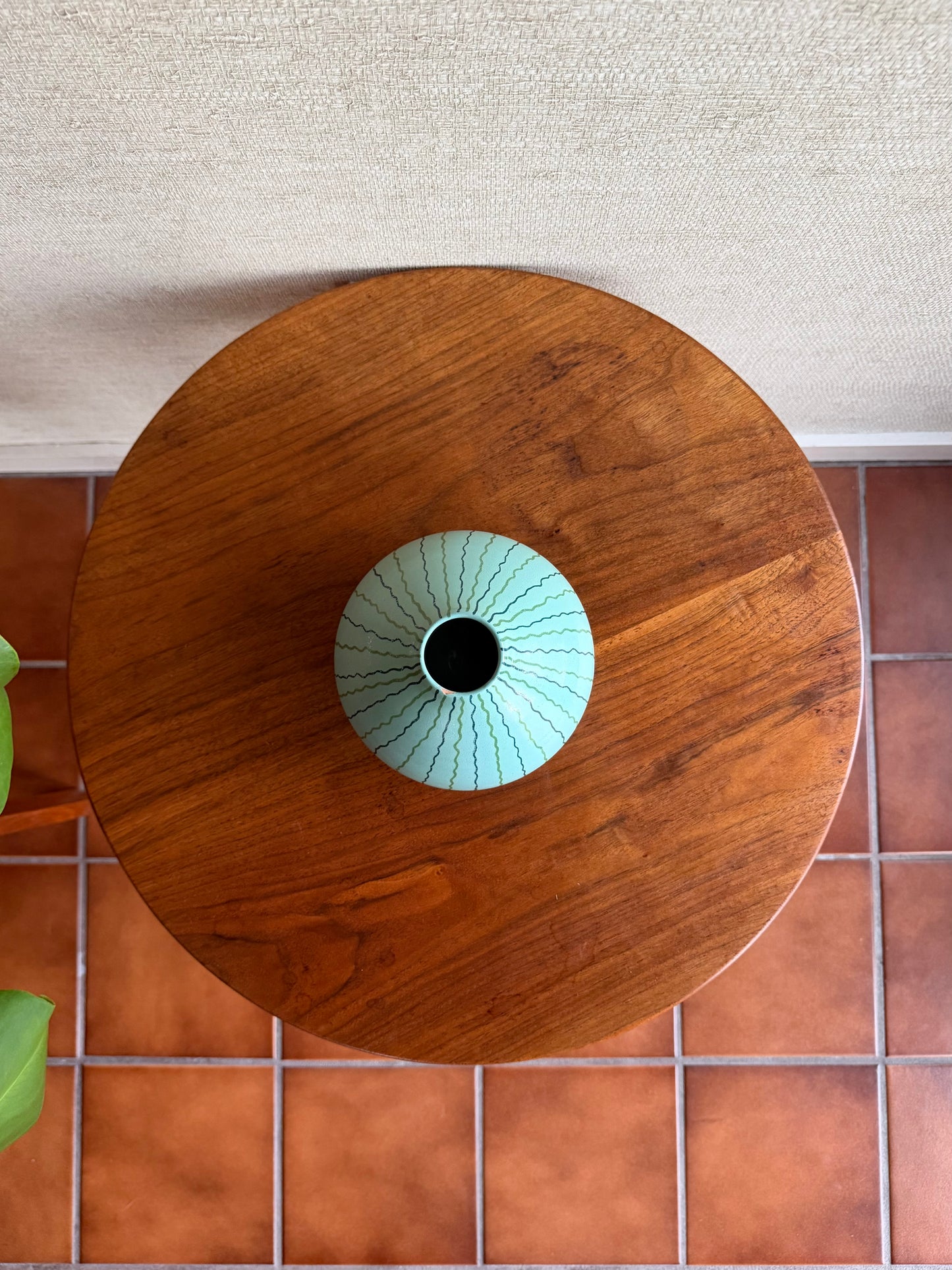 Wooden table with a ceramic vase on a tiled floor