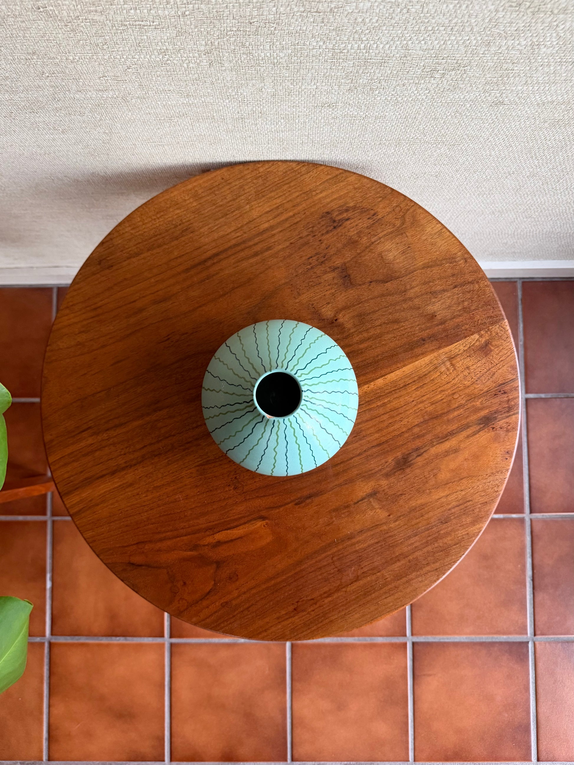 Wooden table with a ceramic vase on a tiled floor
