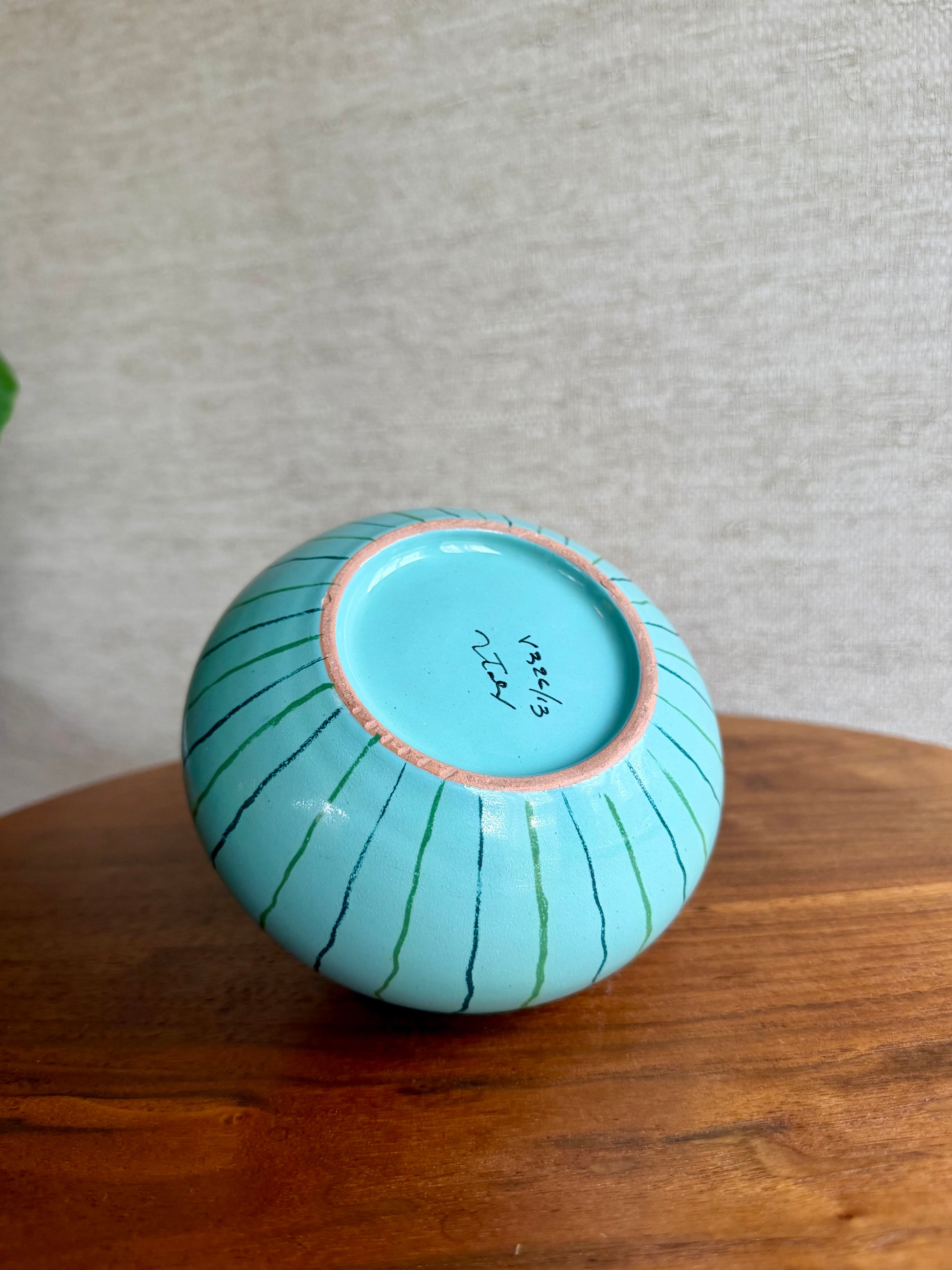 Turquoise ceramic bowl with decorative lines on a wooden surface