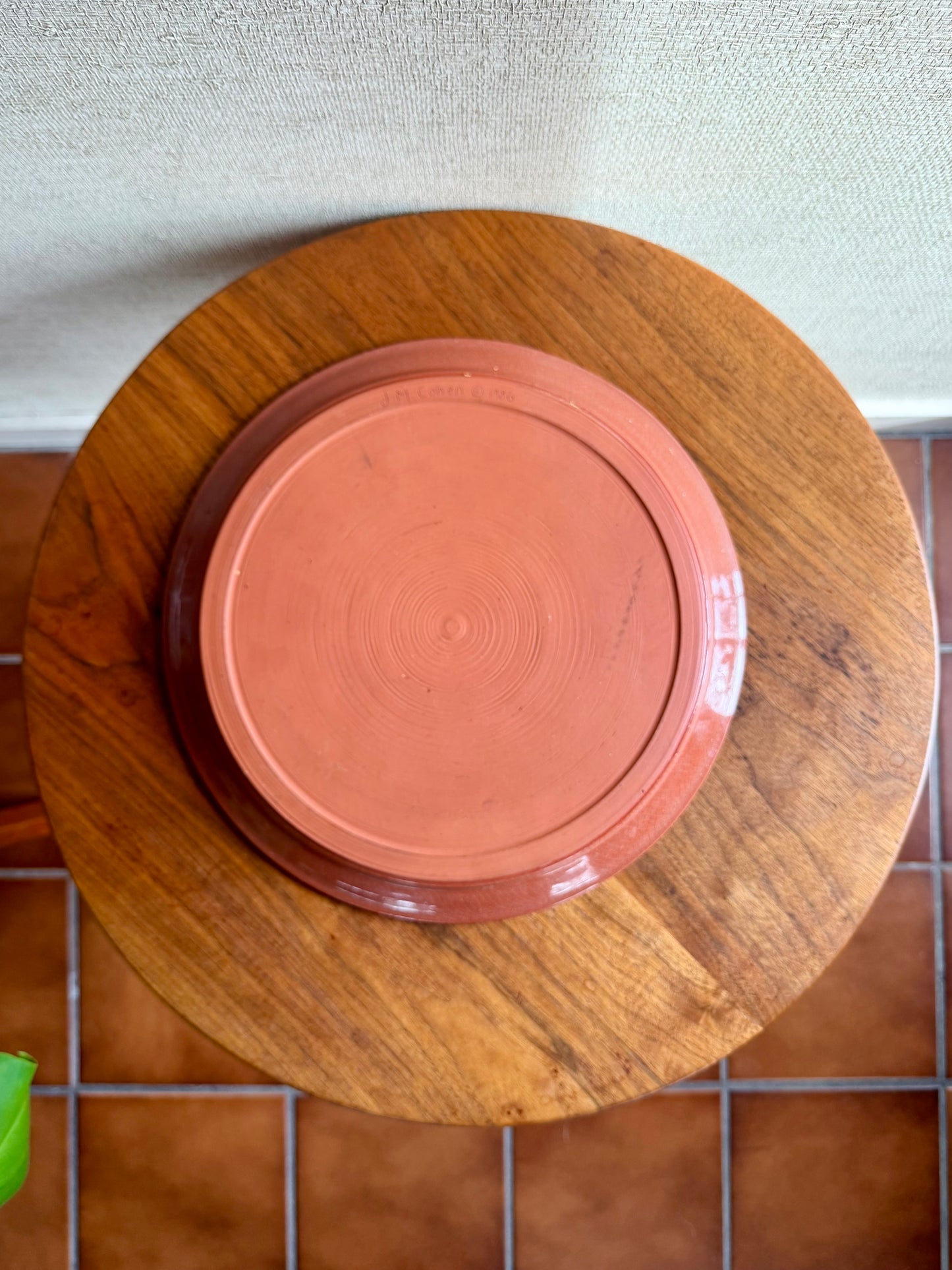 Terracotta plate on a wooden stand with a tiled floor background
