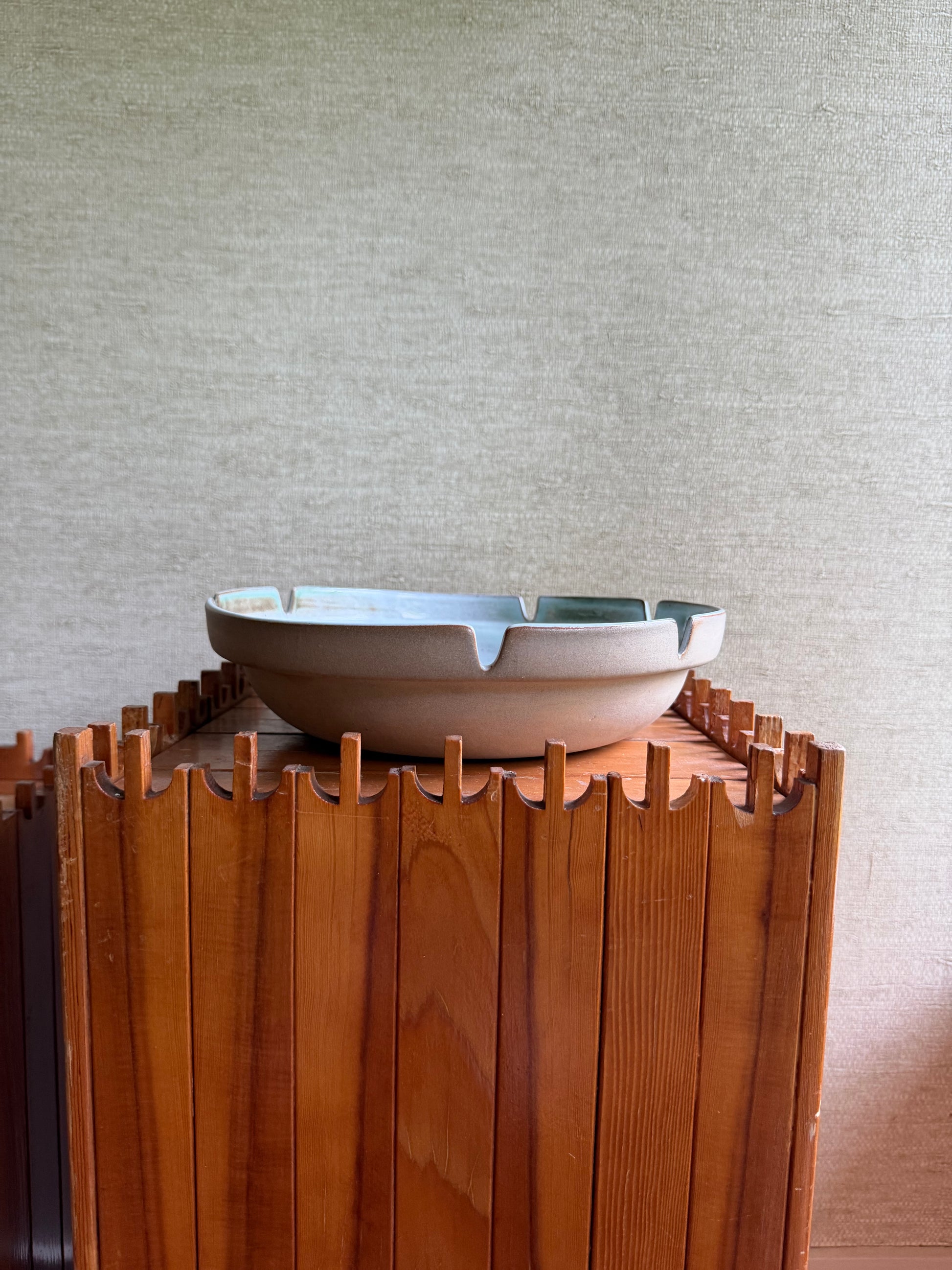 Wooden slatted shelf against a neutral wall