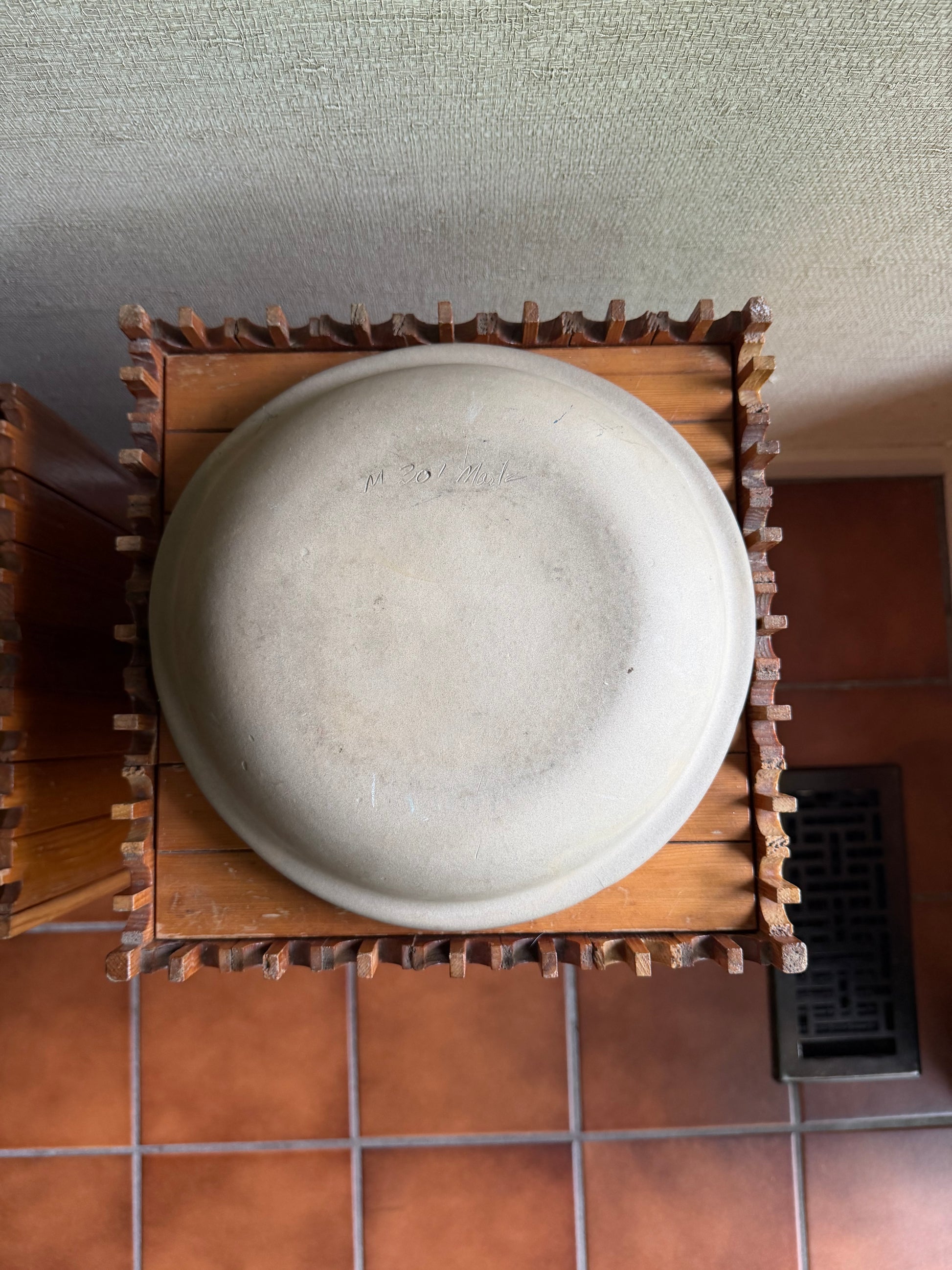 Round stone on a wooden stand against a tiled wall