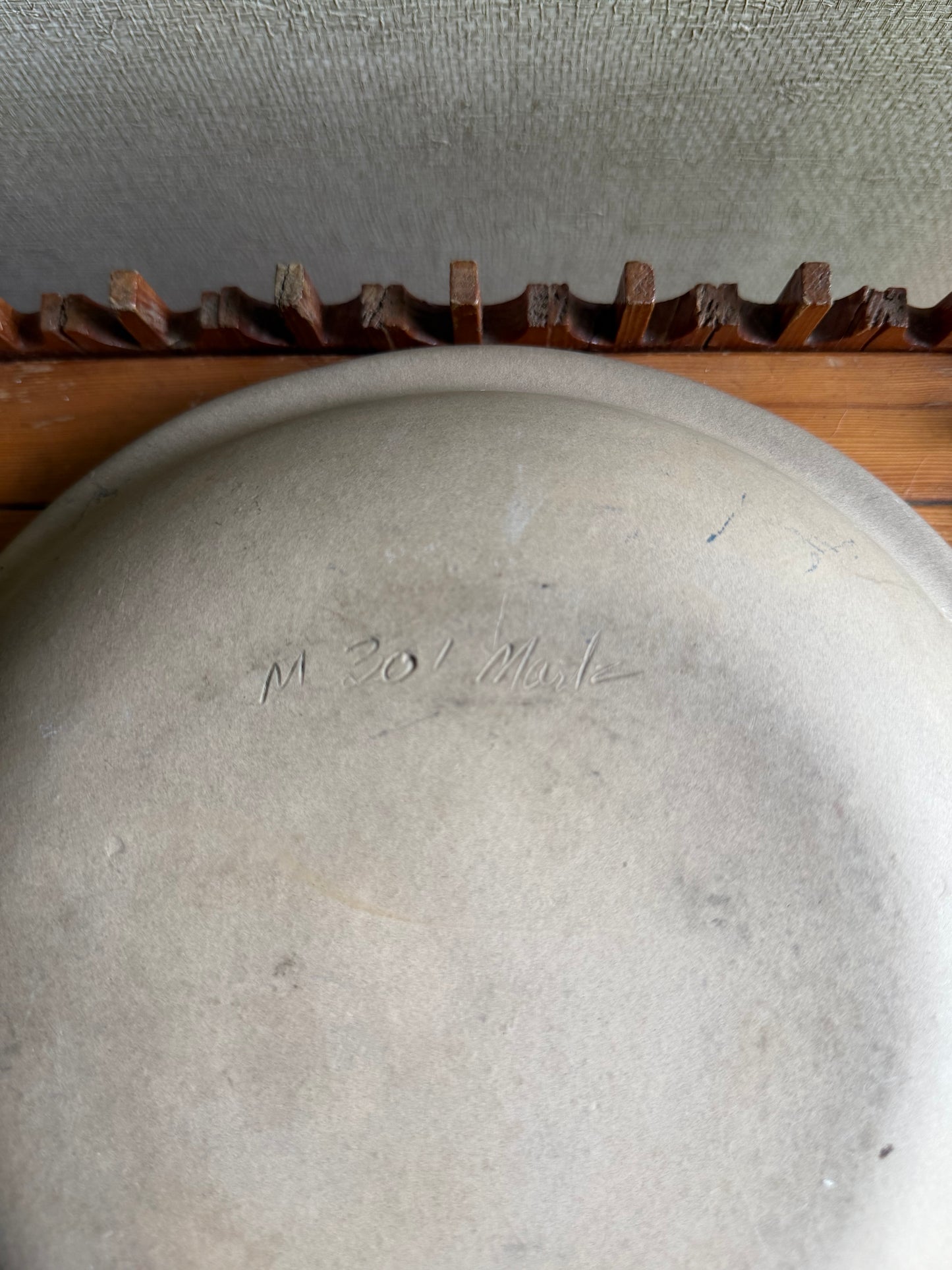 Close-up of a ceramic plate with 'M 301 Martz' engraving on a textured surface.