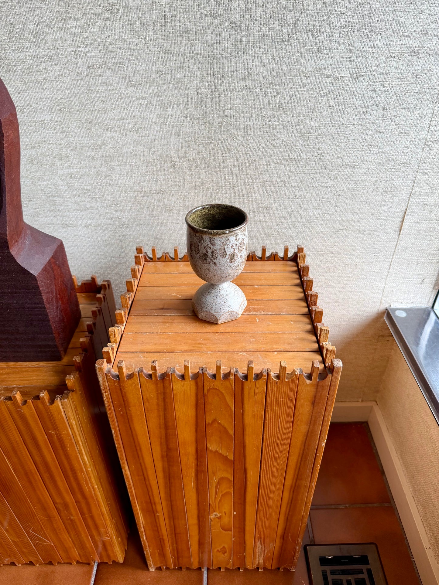 Wooden cabinet with decorative items against a textured wall