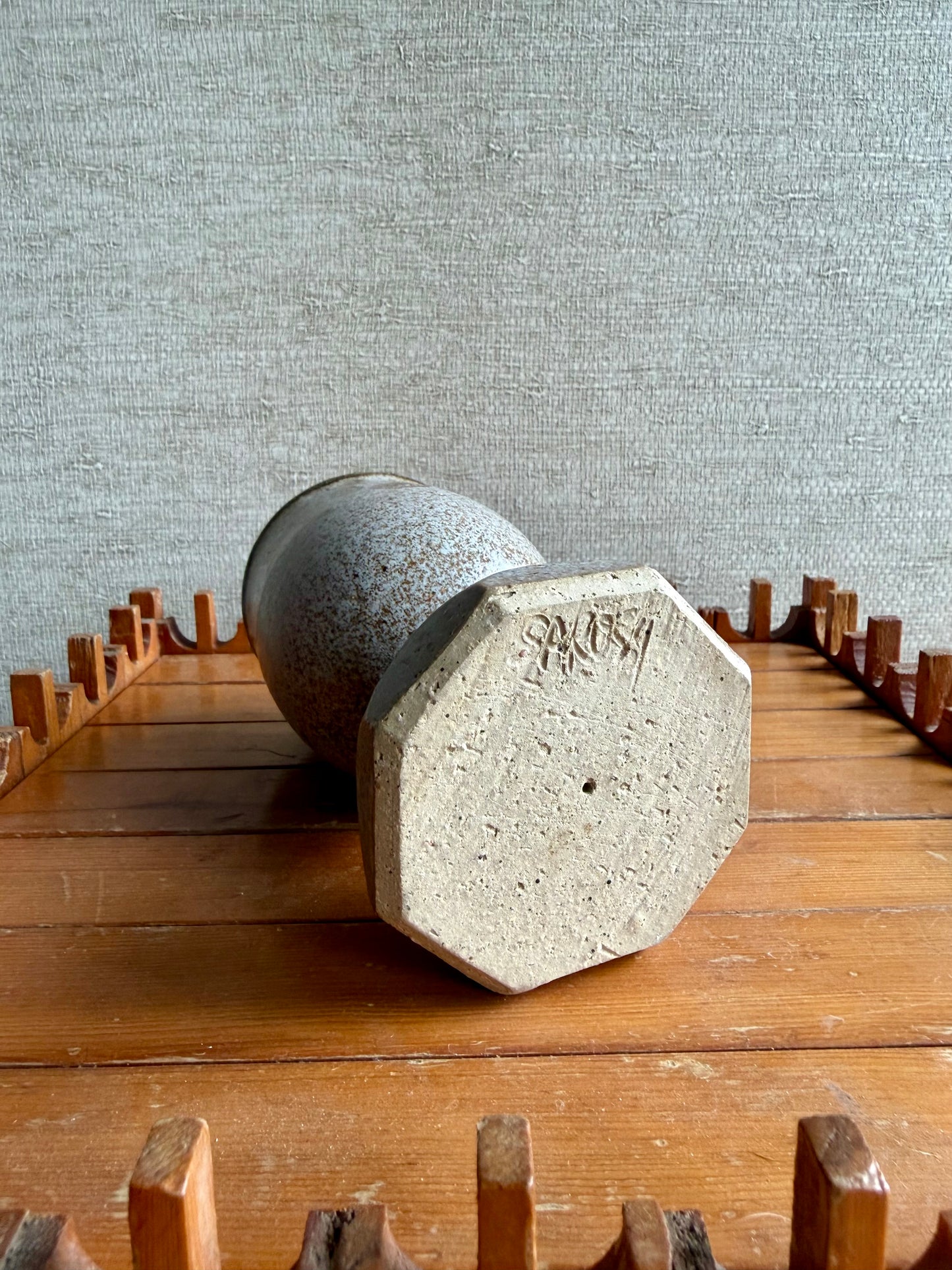 pottery goblet on a wooden surface with a textured gray wall background