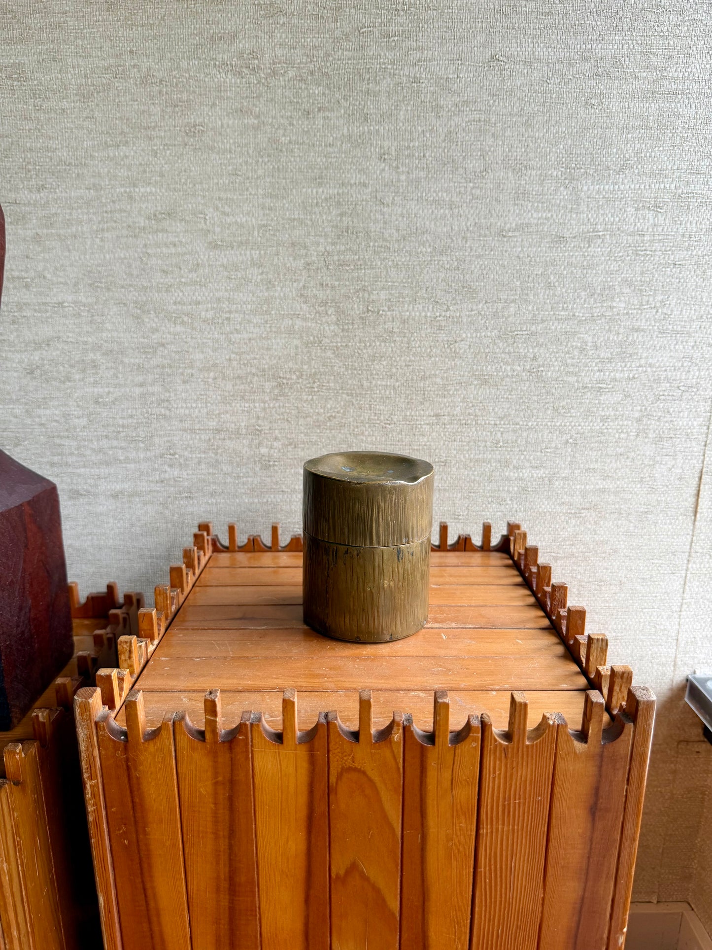 Wooden crate with a metallic cup on top against a textured wall.