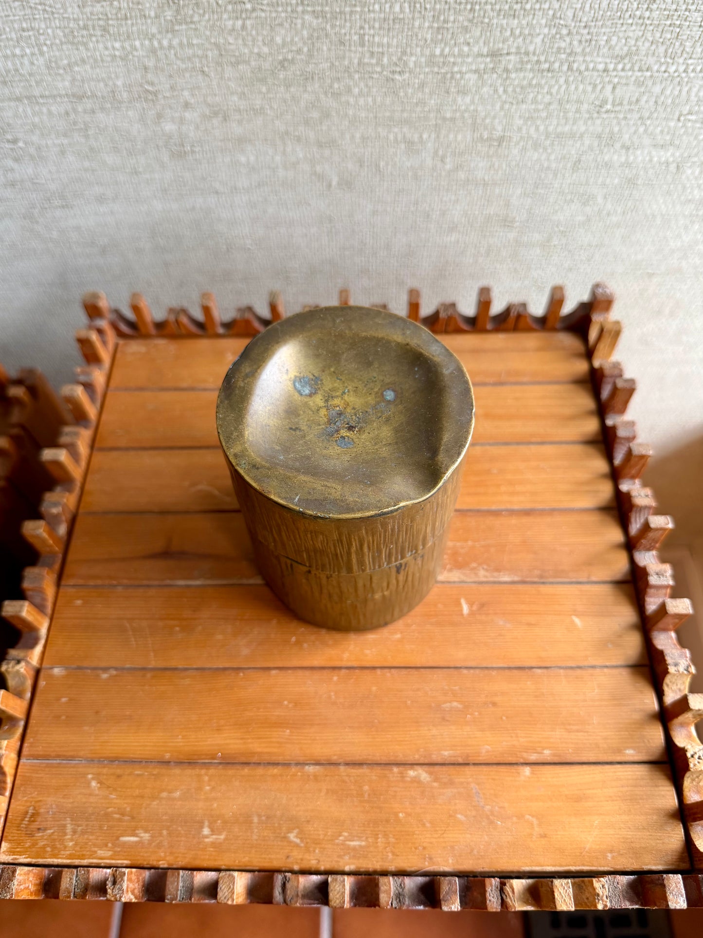 Brass cup on a wooden stand with a textured background
