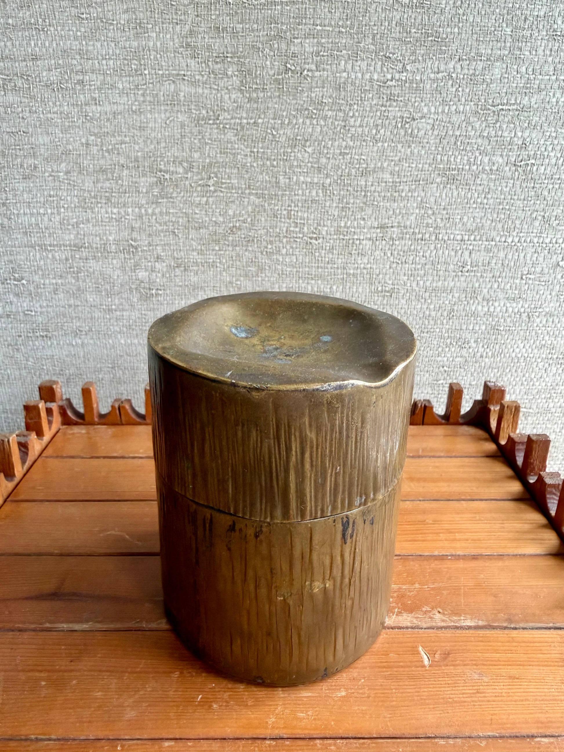 Wooden cylindrical object on a wooden surface with a textured gray wall background