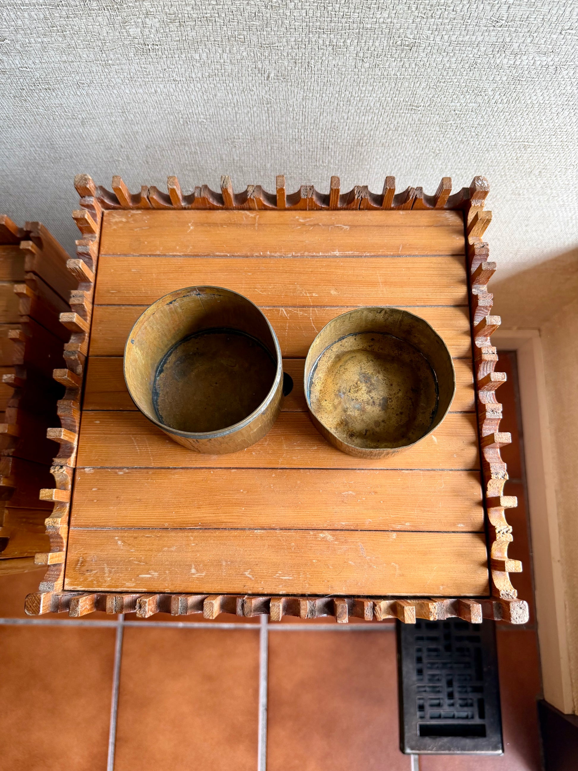 Two wooden bowls on a wooden stand with a textured wall background