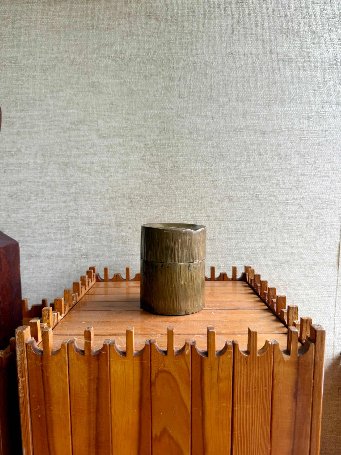 Brass tobacco canister on a textured surface with a neutral background