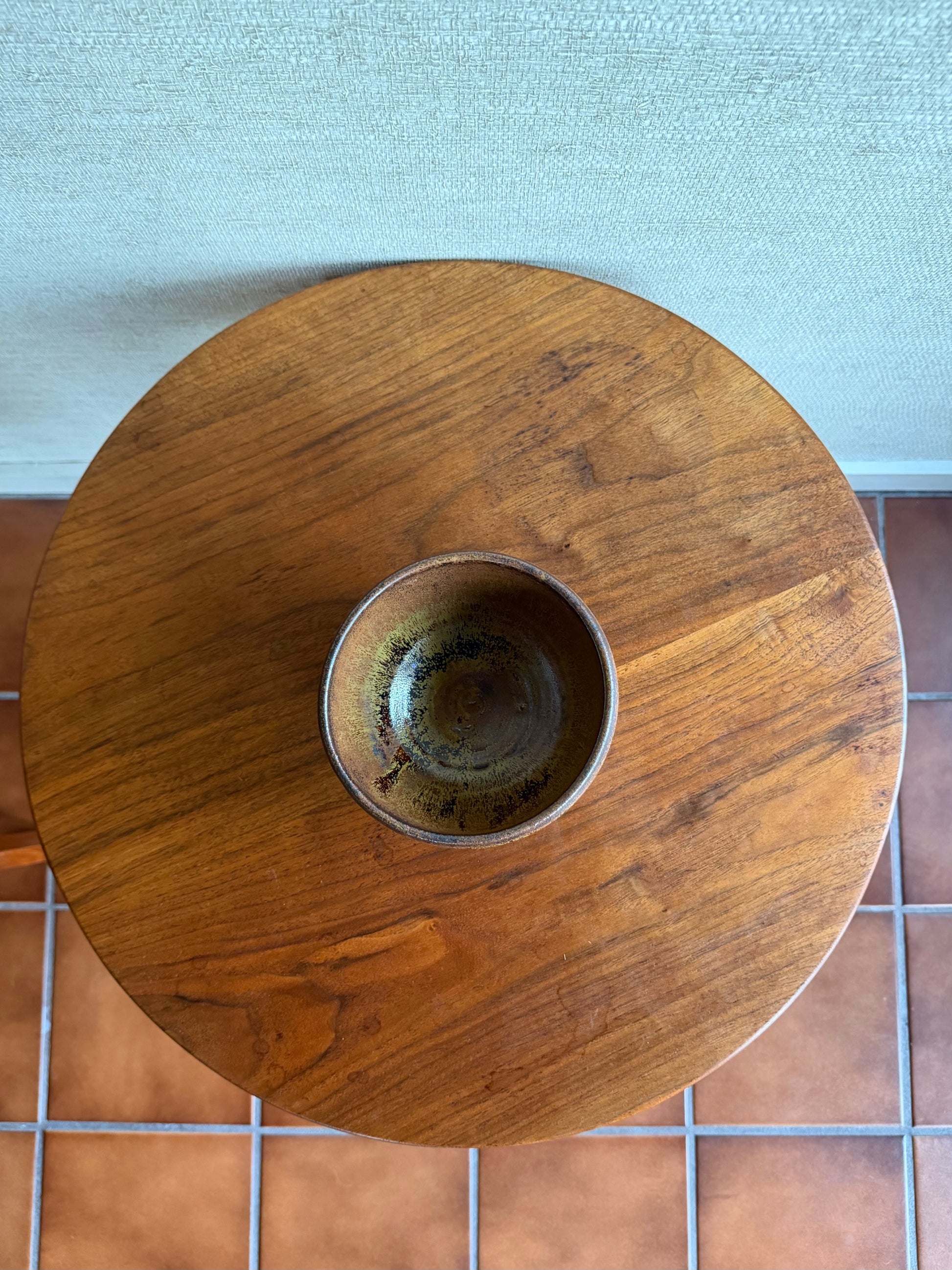 Wooden table with a textured surface on a tiled floor