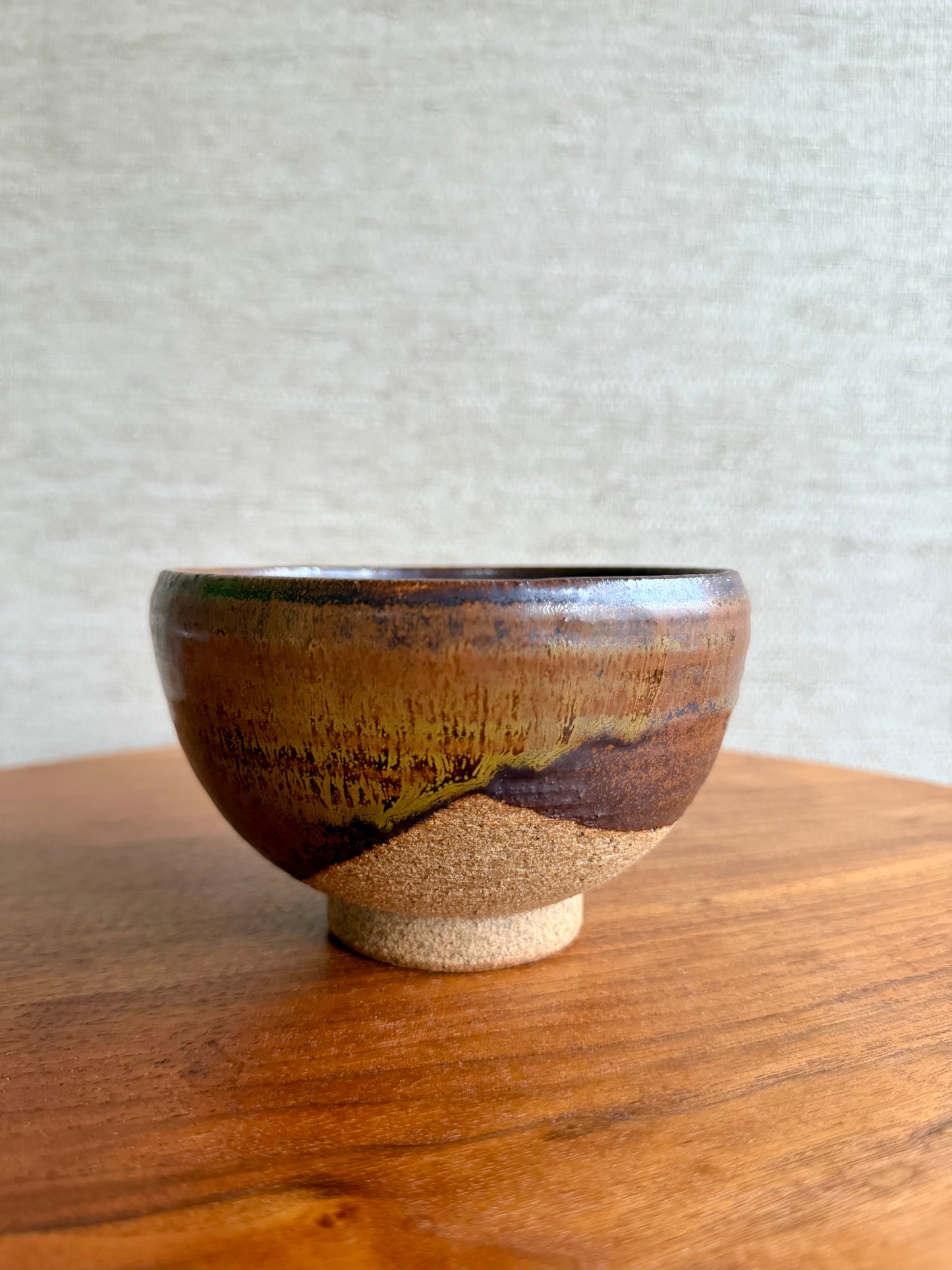 Ceramic bowl with brown and beige glaze on a wooden surface