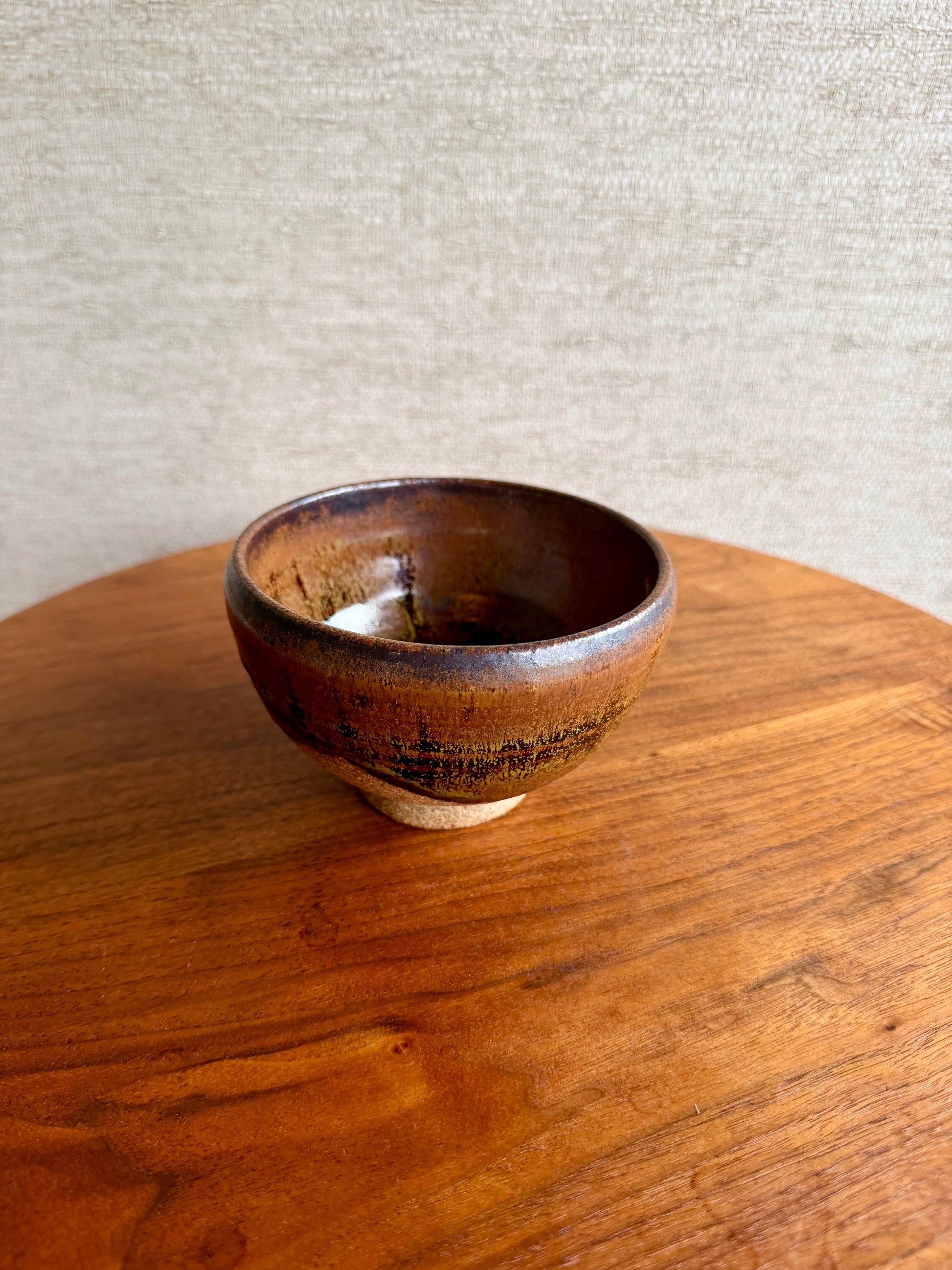 Brown ceramic bowl on a wooden surface with a neutral background