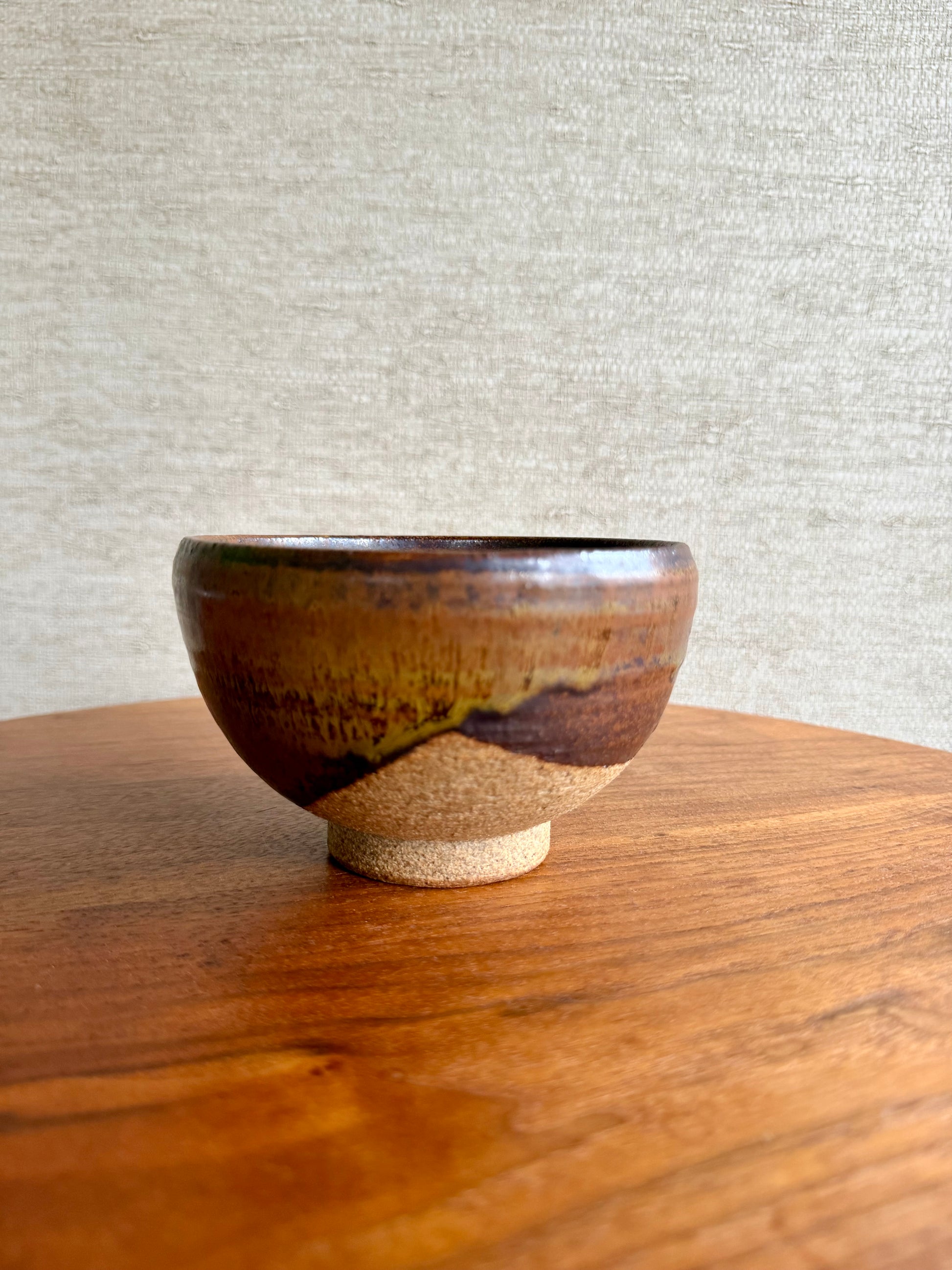 Ceramic bowl with a brown and beige design on a wooden surface with a gray textured background