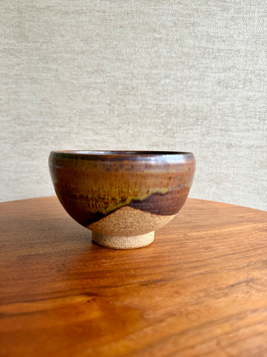 Ceramic bowl with a brown and beige design on a wooden surface with a gray textured background