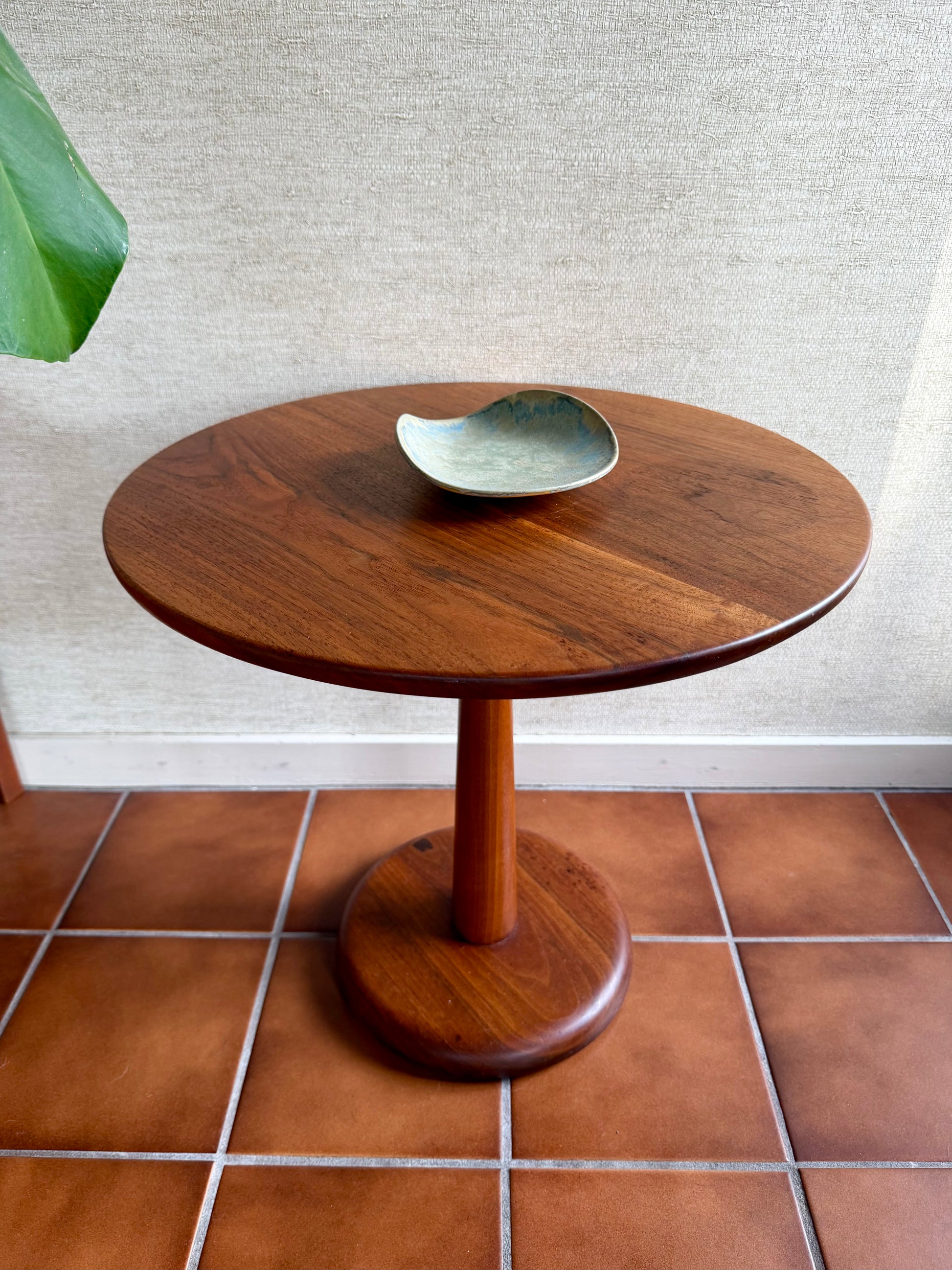 Wooden side table with a bowl on a tiled floor