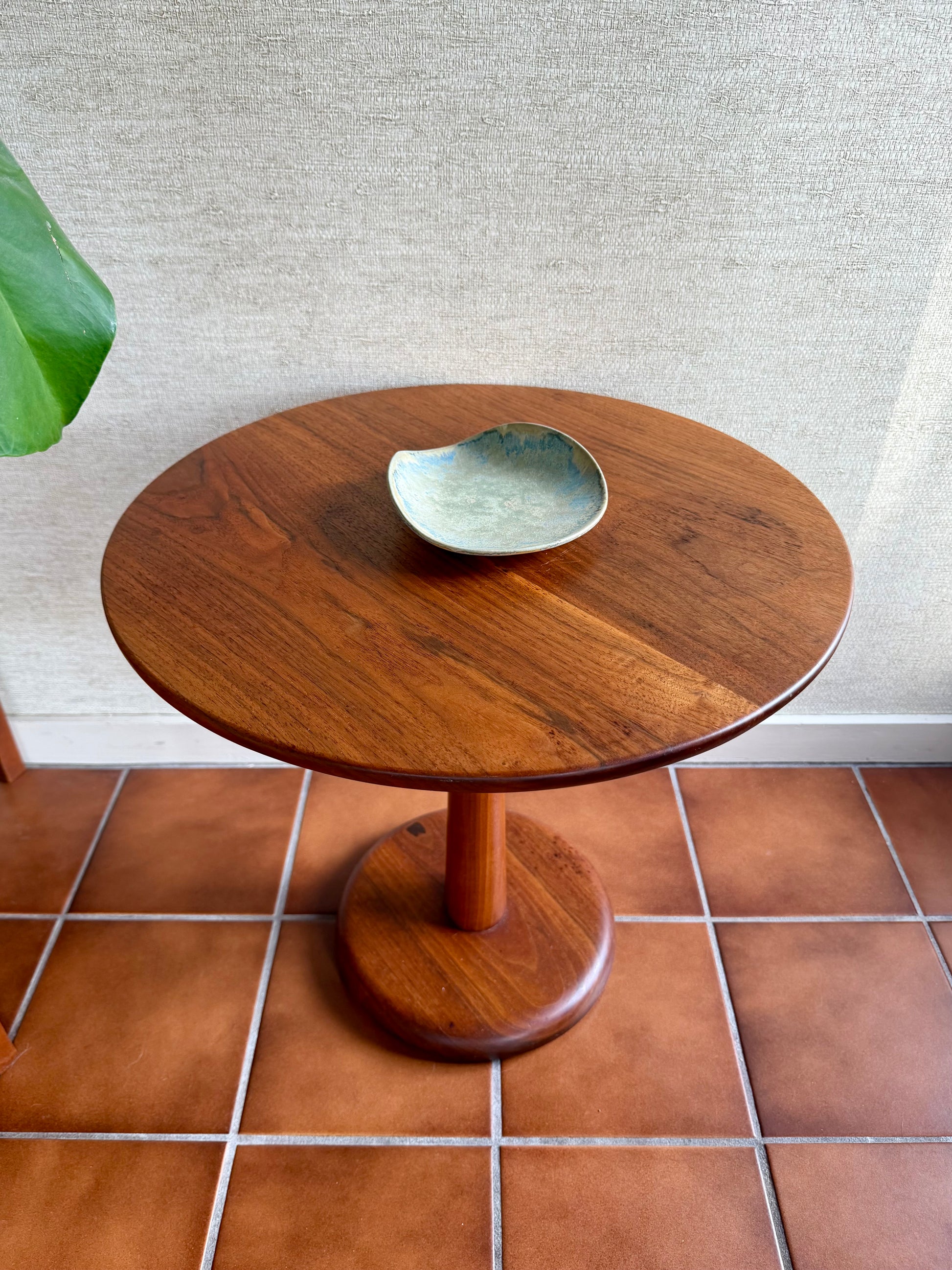 Wooden side table with a ceramic bowl on a tiled floor