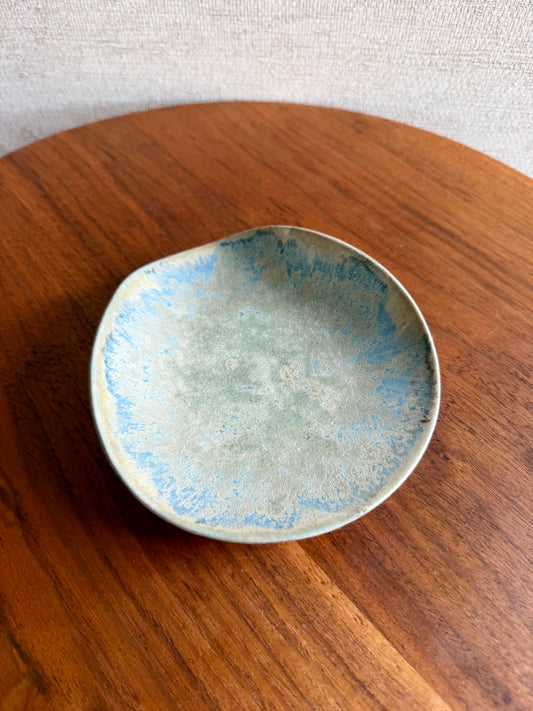 Ceramic dish with blue and green glaze on a wooden surface