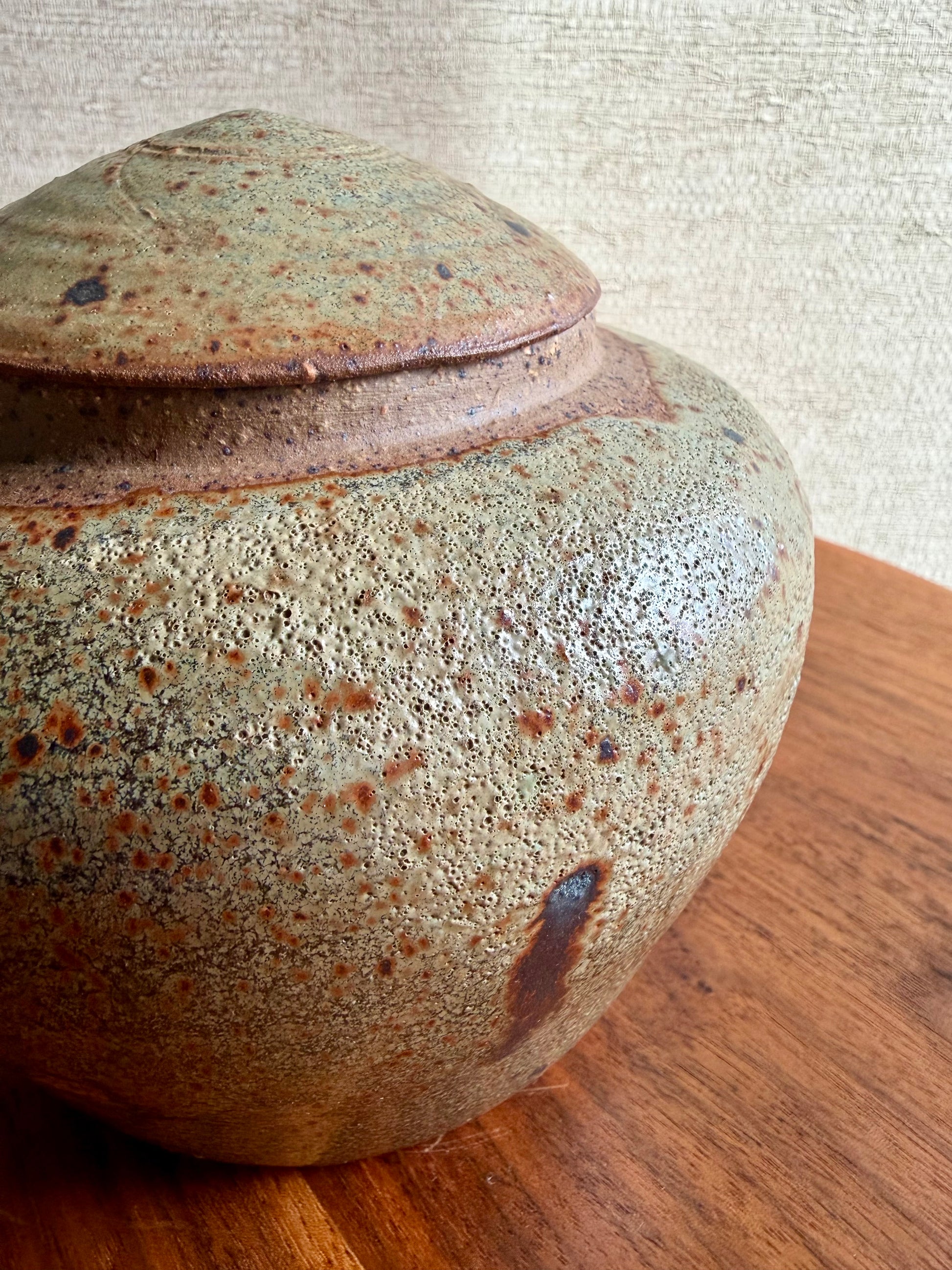 Stoneware jar with a textured surface on a wooden surface