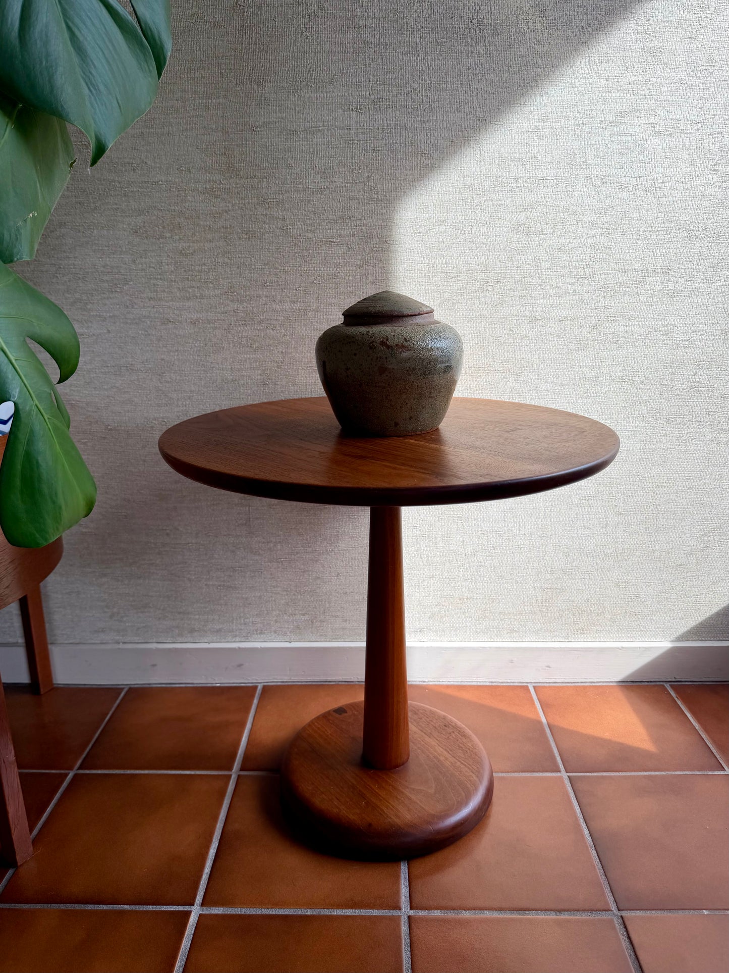 Wooden side table with a ceramic vase on a tiled floor