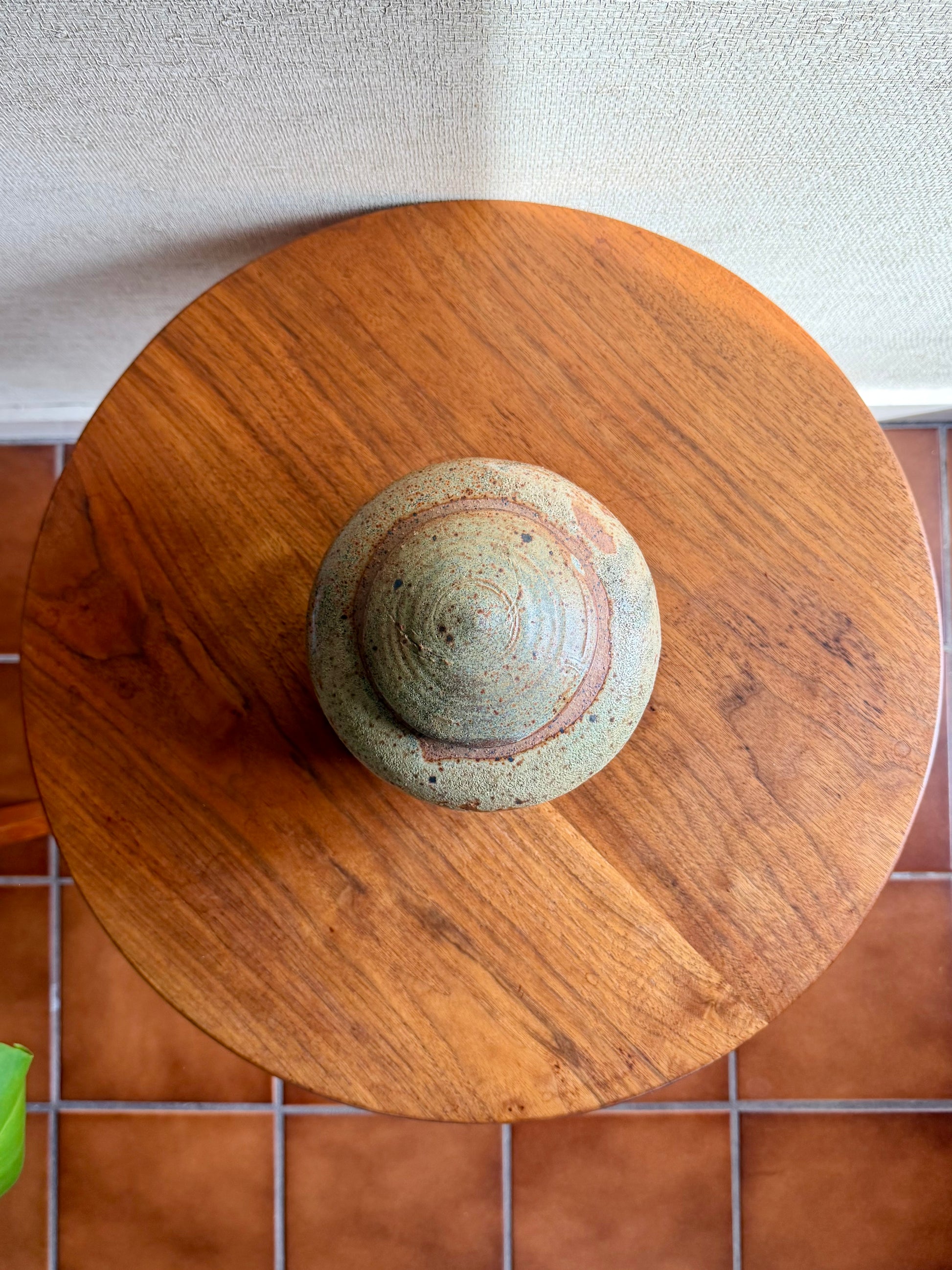 Ceramic object on a wooden surface with a tiled floor background