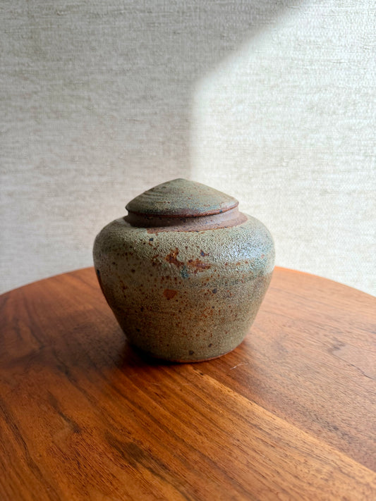 Small ceramic jar with a lid on a wooden surface