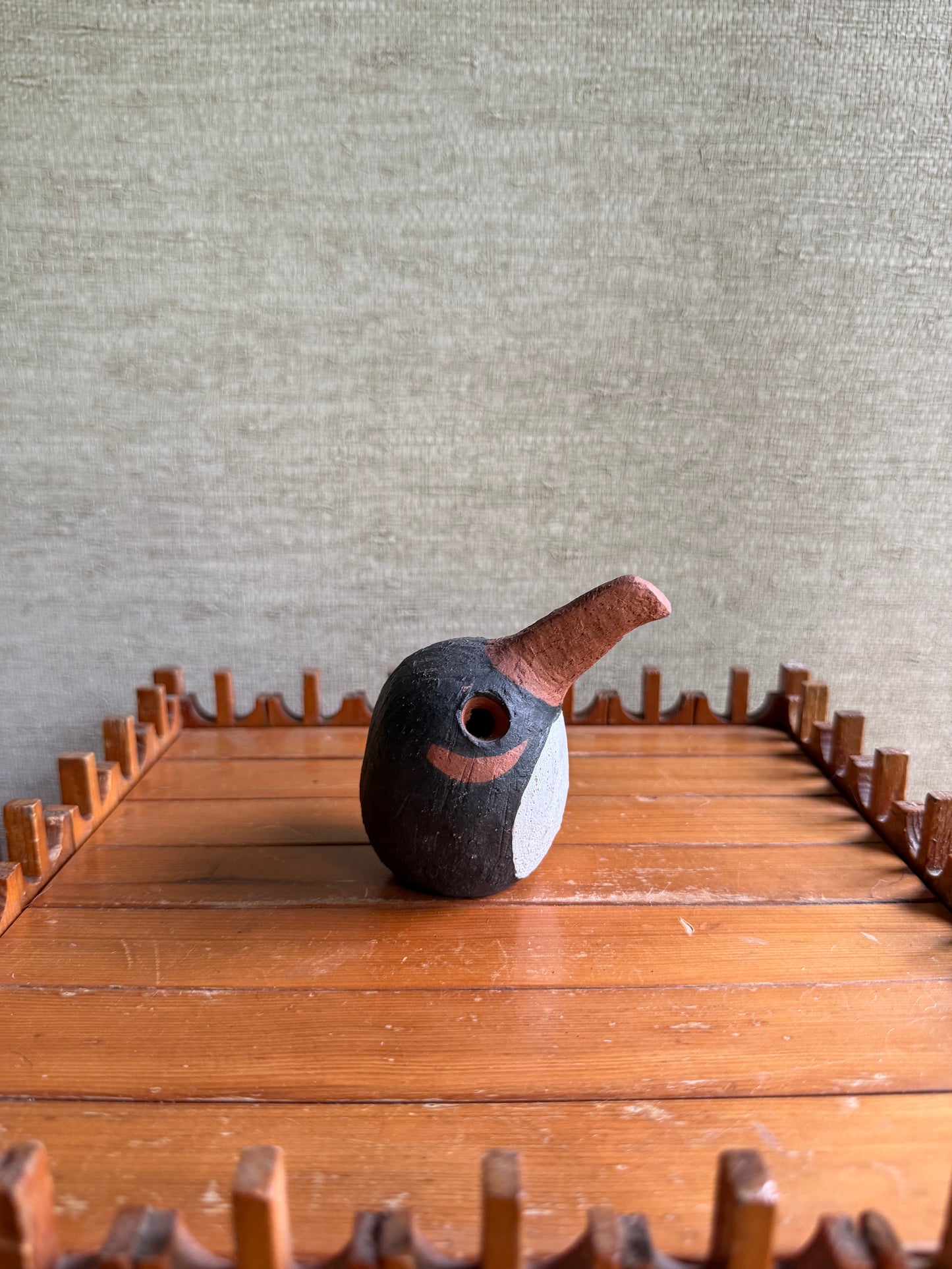 Decorative birdhouse on a wooden surface with a textured wall background