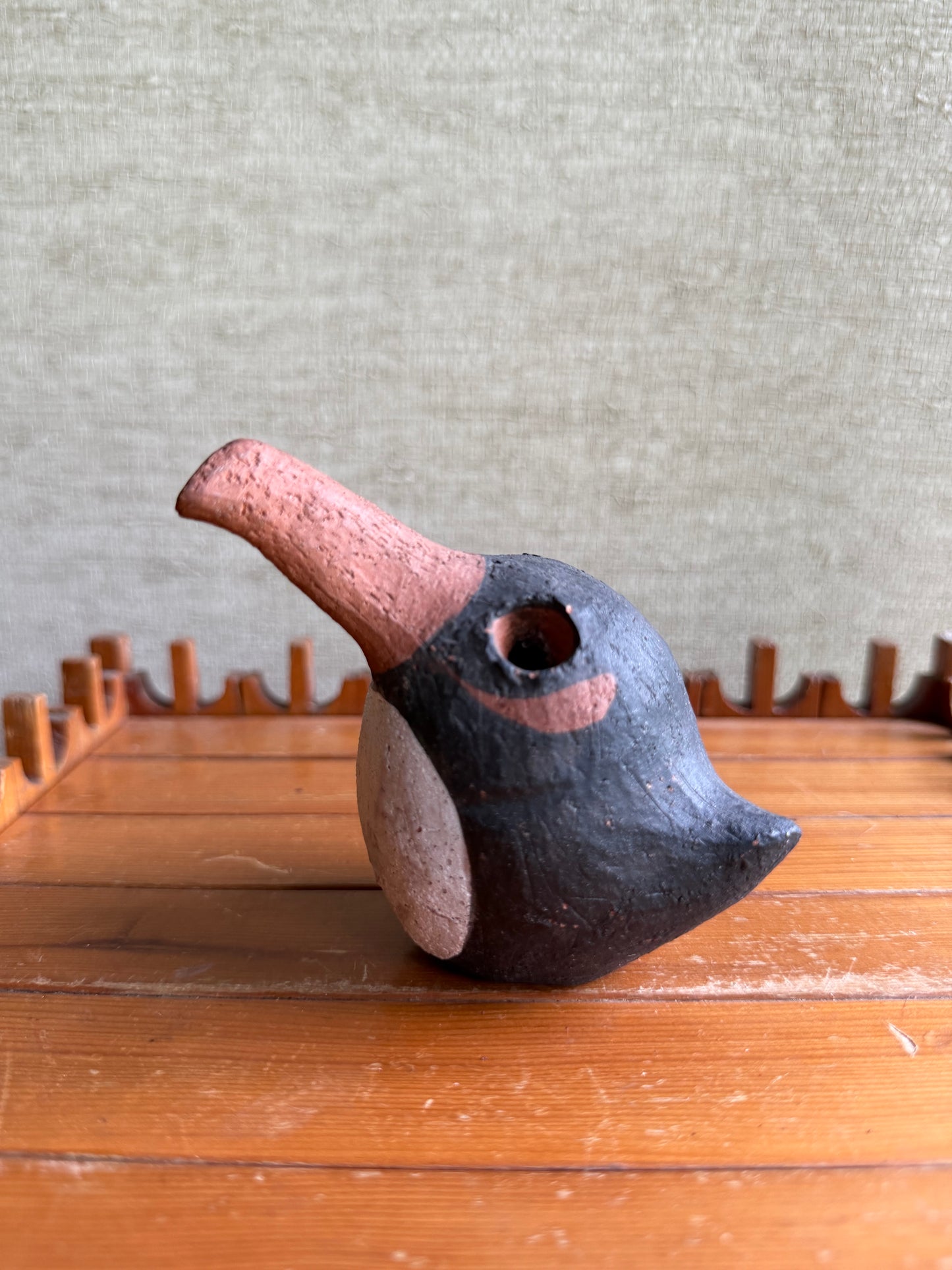 Ceramic bird with a unique design on a wooden surface