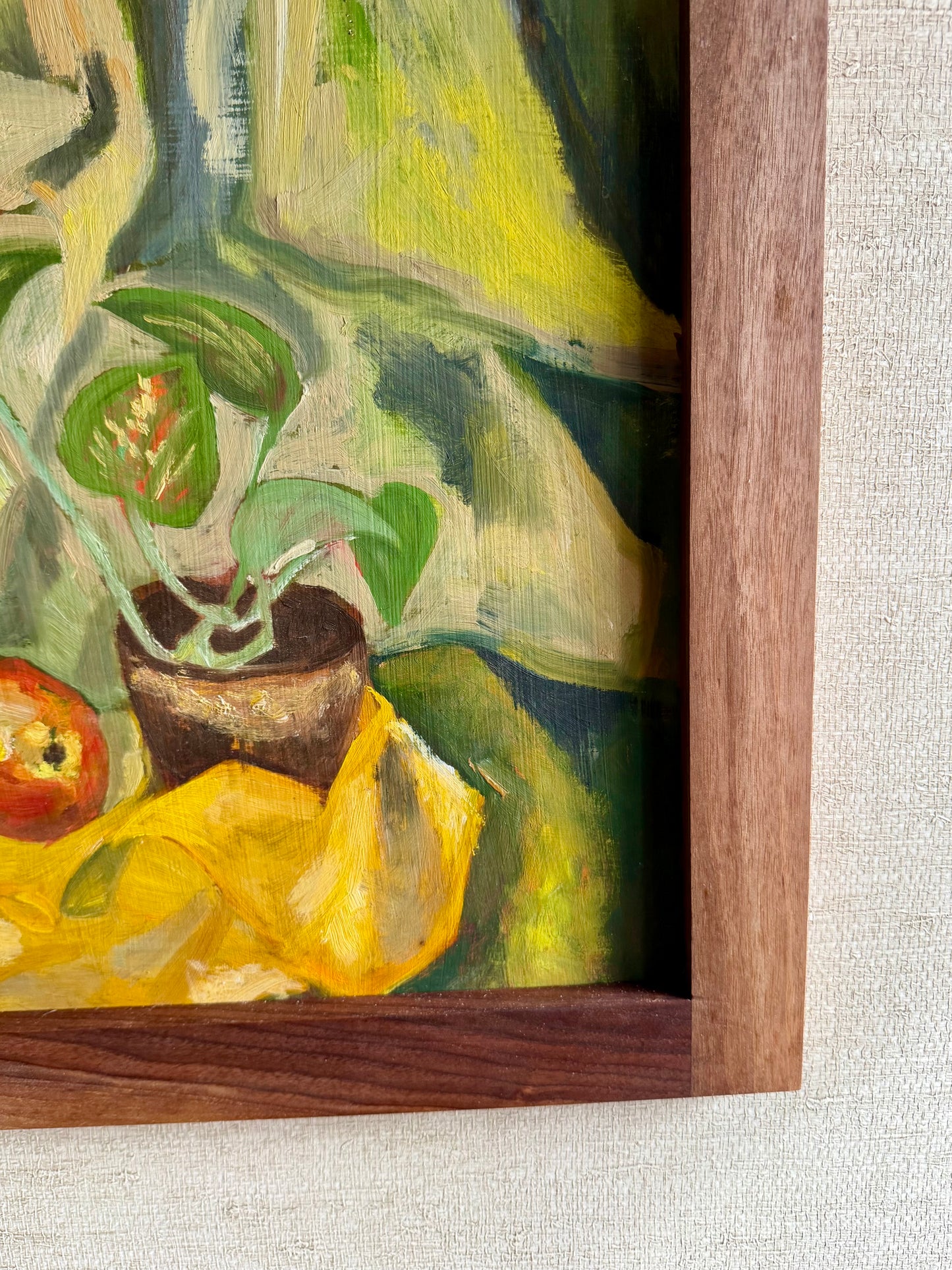 Close-up of a painting with a wooden frame on a textured wall.
