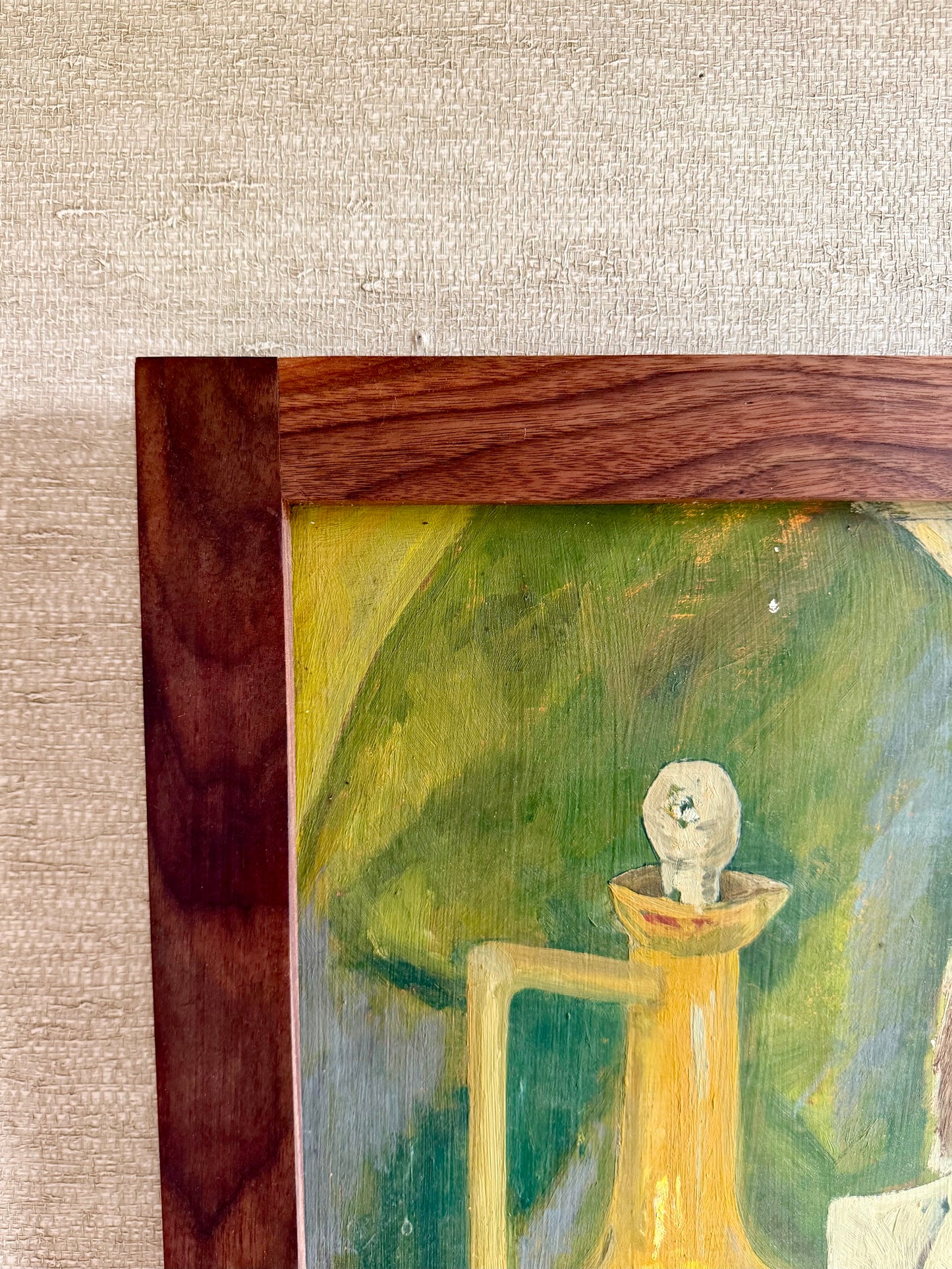 Close-up of a painting with a wooden frame on a textured beige wall.