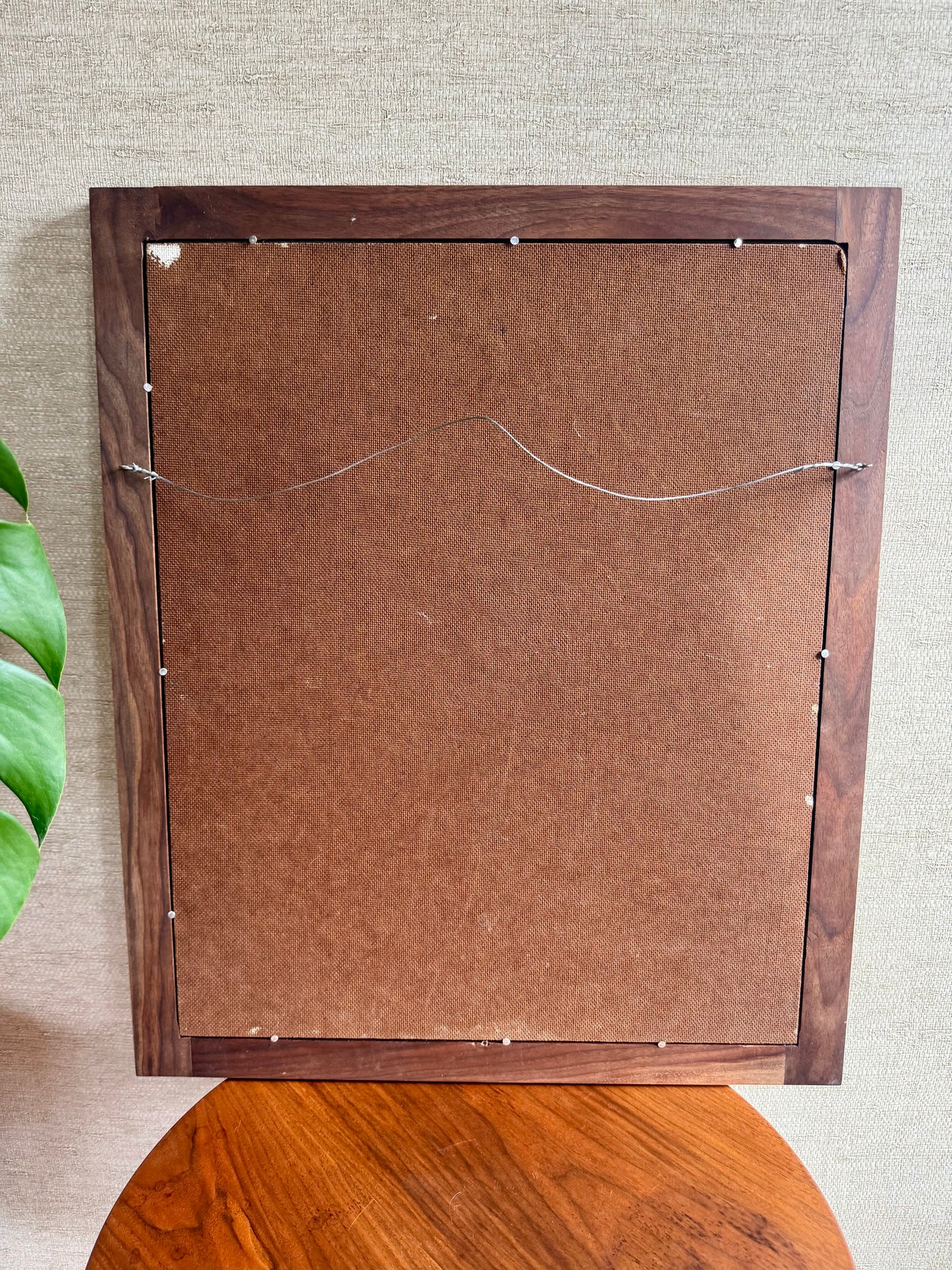 Back view of a wooden picture frame on a textured wall.