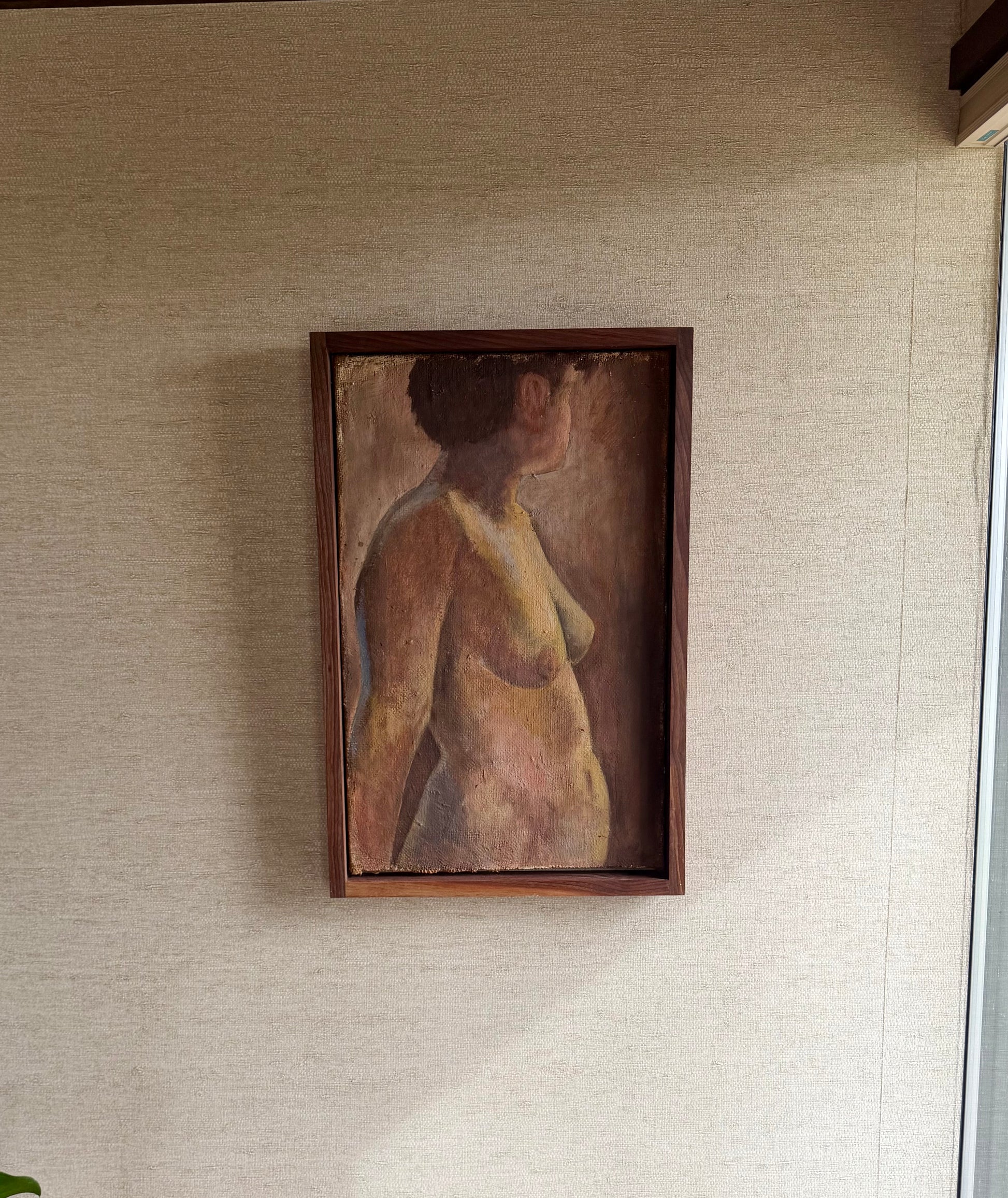 Framed painting of a nude figure on a textured wall.