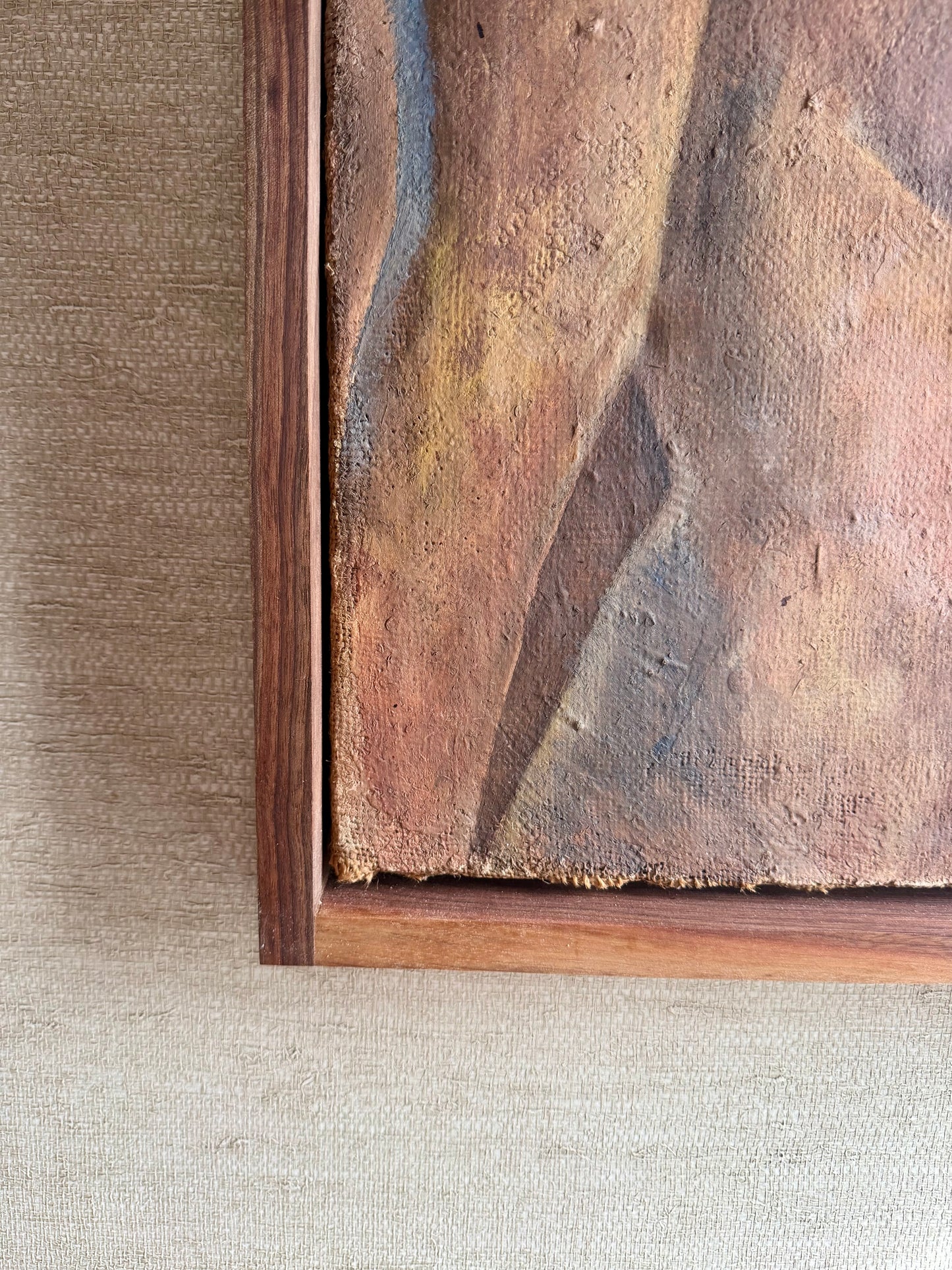 Close-up of a textured painting with a wooden frame on a neutral background