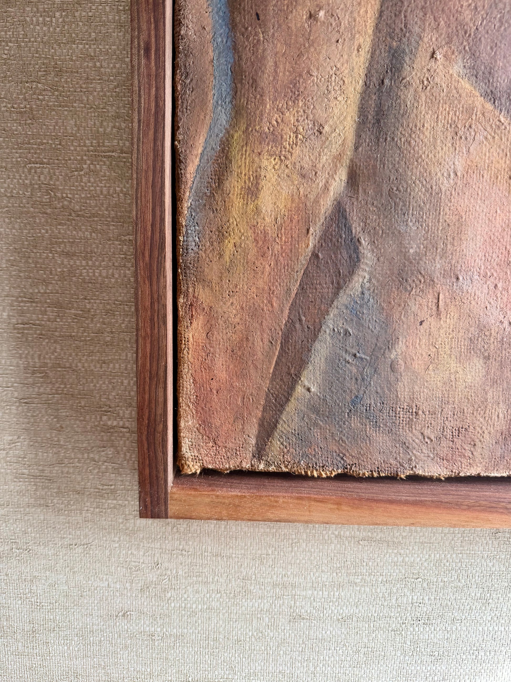 Close-up of a textured painting with a wooden frame on a neutral background