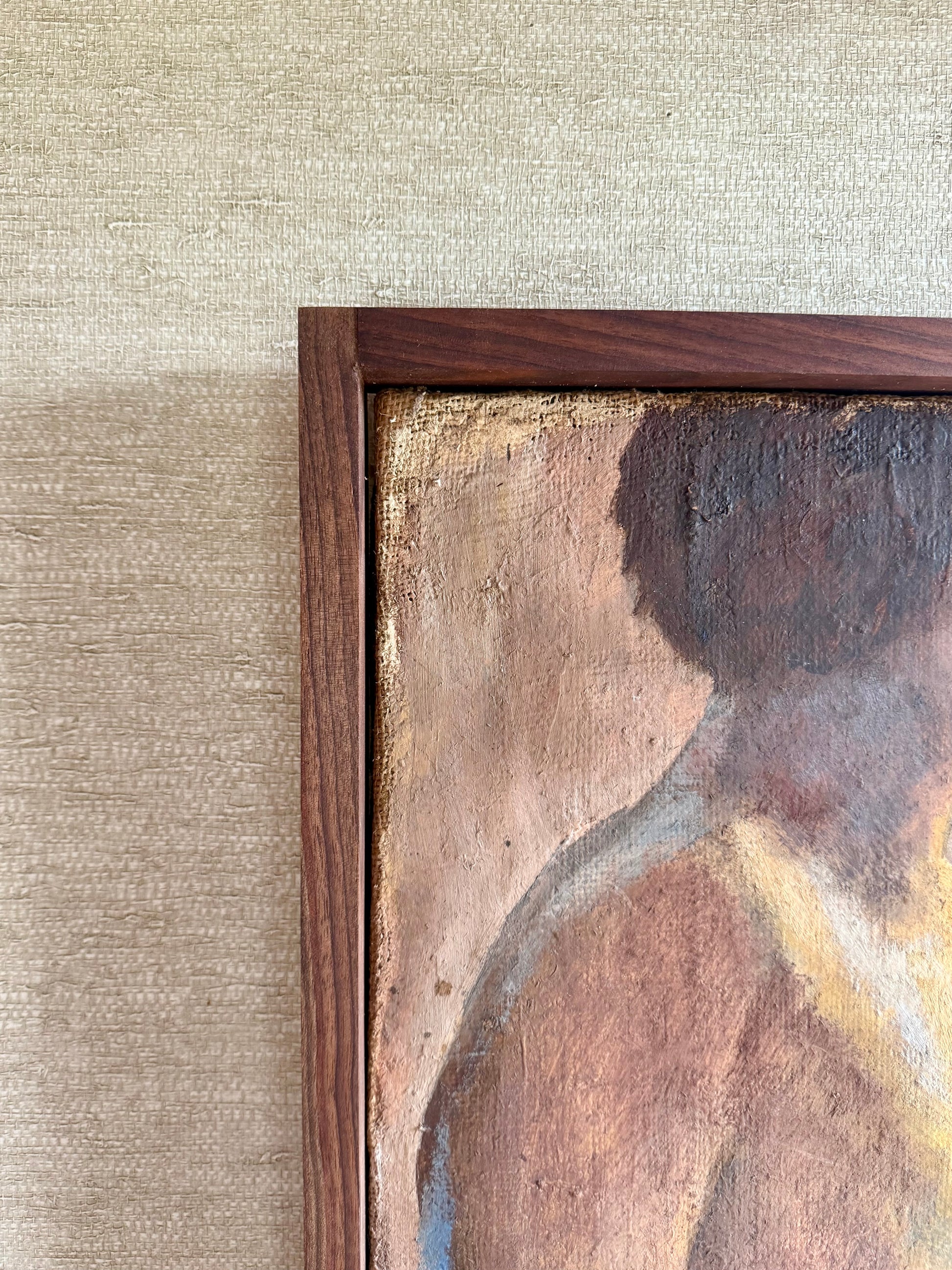 Close-up of a framed painting on a textured wall.