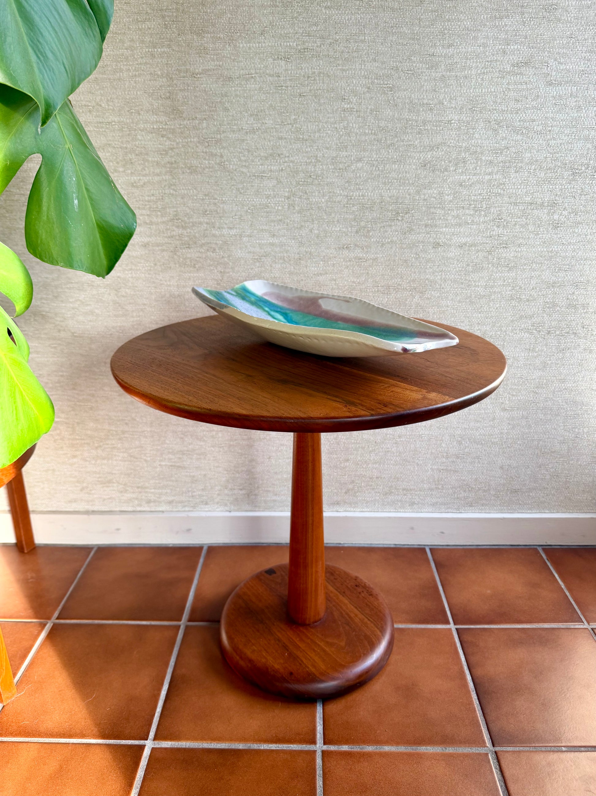 Wooden side table with a decorative bowl on a tiled floor