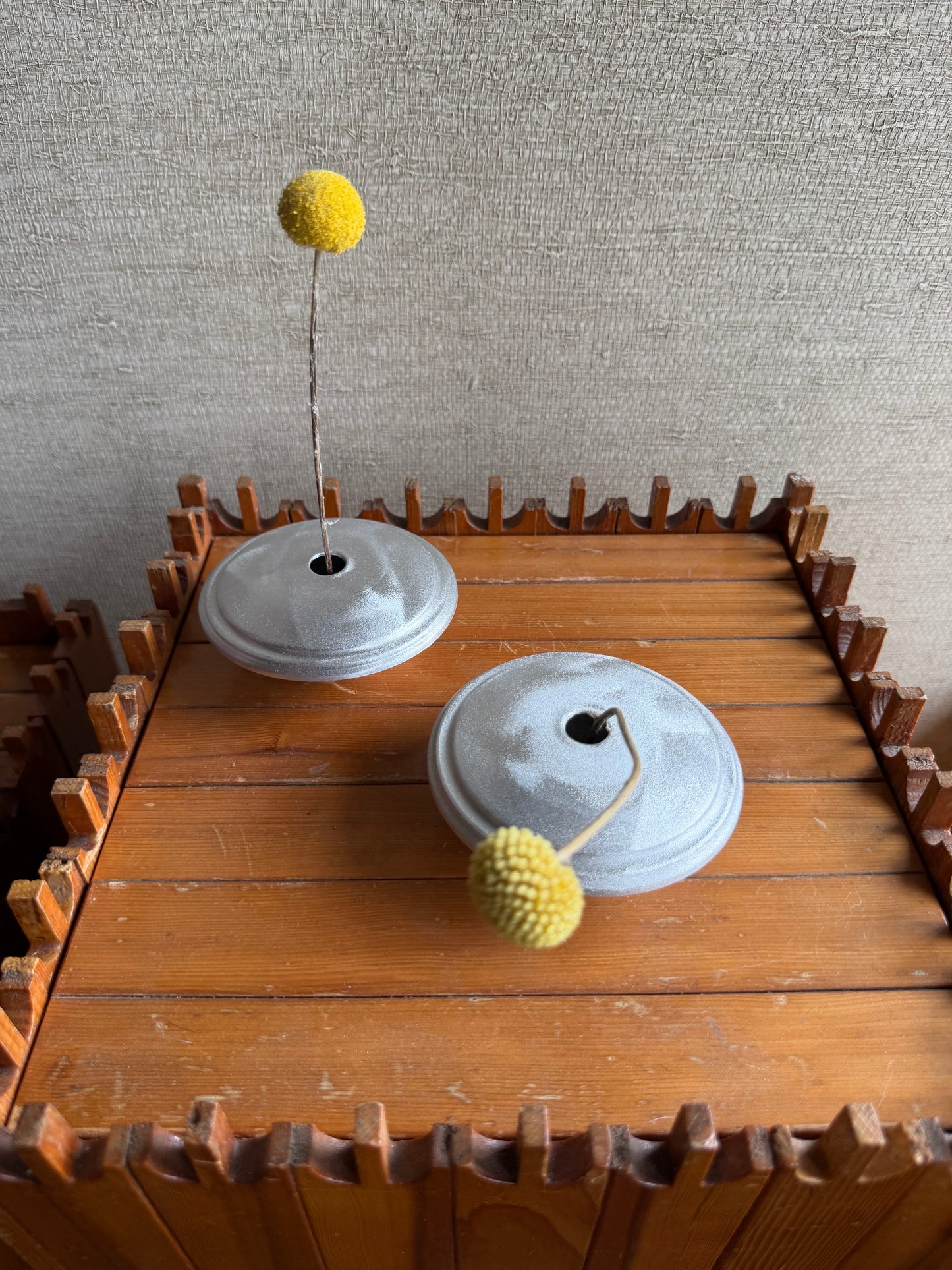Wooden wall art with gears and yellow balls on a textured wall