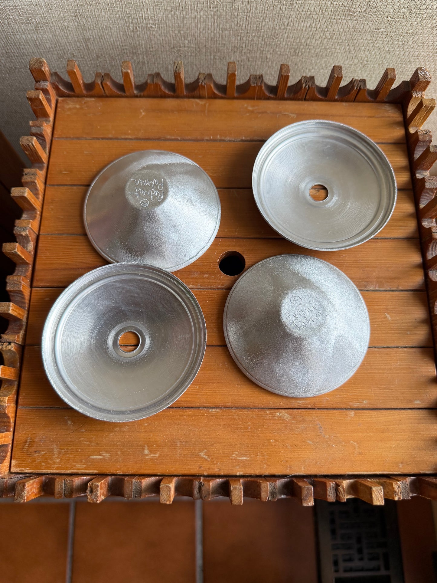 Four metallic bowls on a wooden surface with gears.