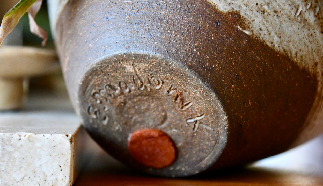 Close-up of a ceramic pot with a visible brand name on a blurred background