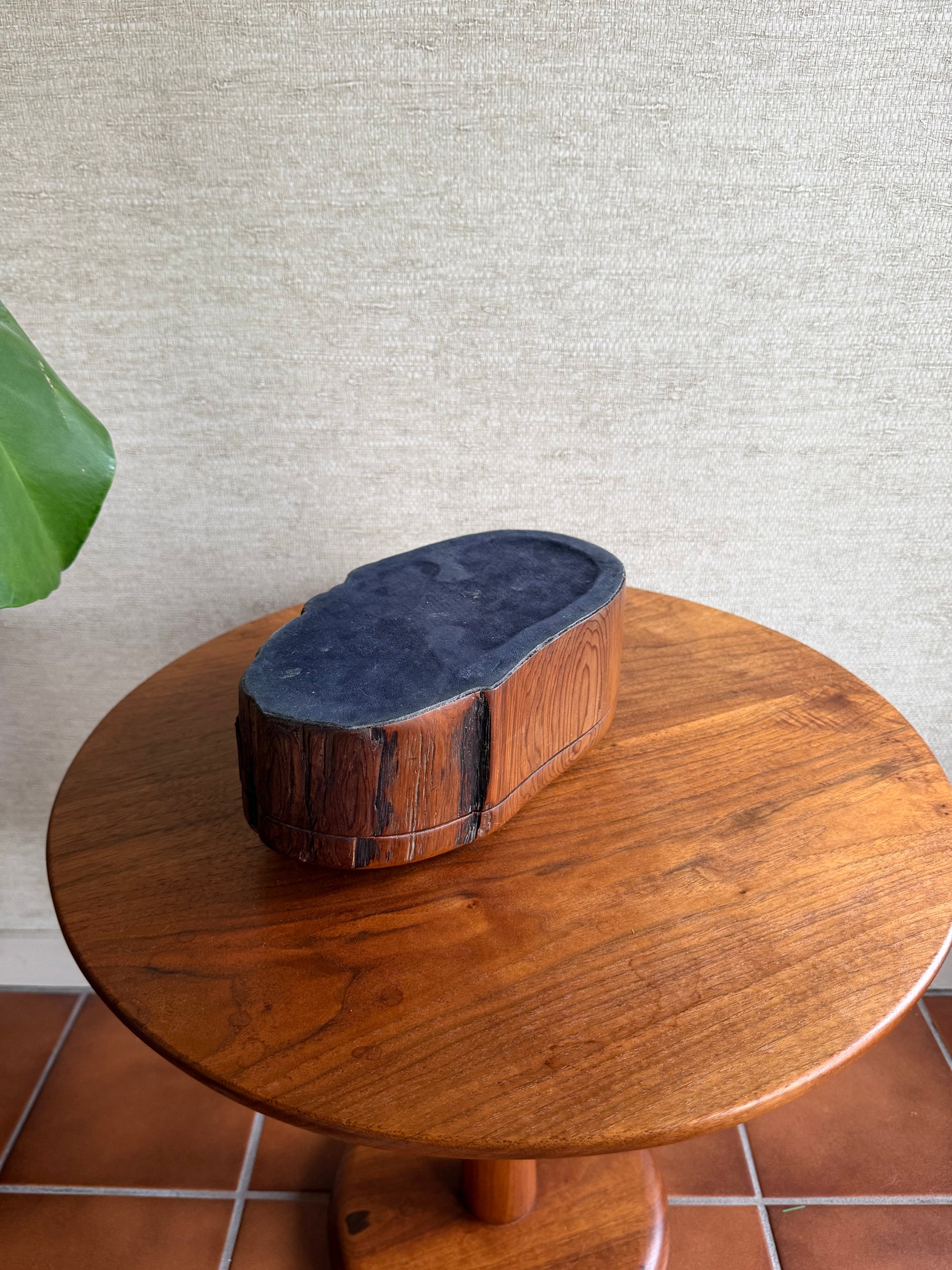Wooden reel with a blue cap on a textured wall and tiled floor background