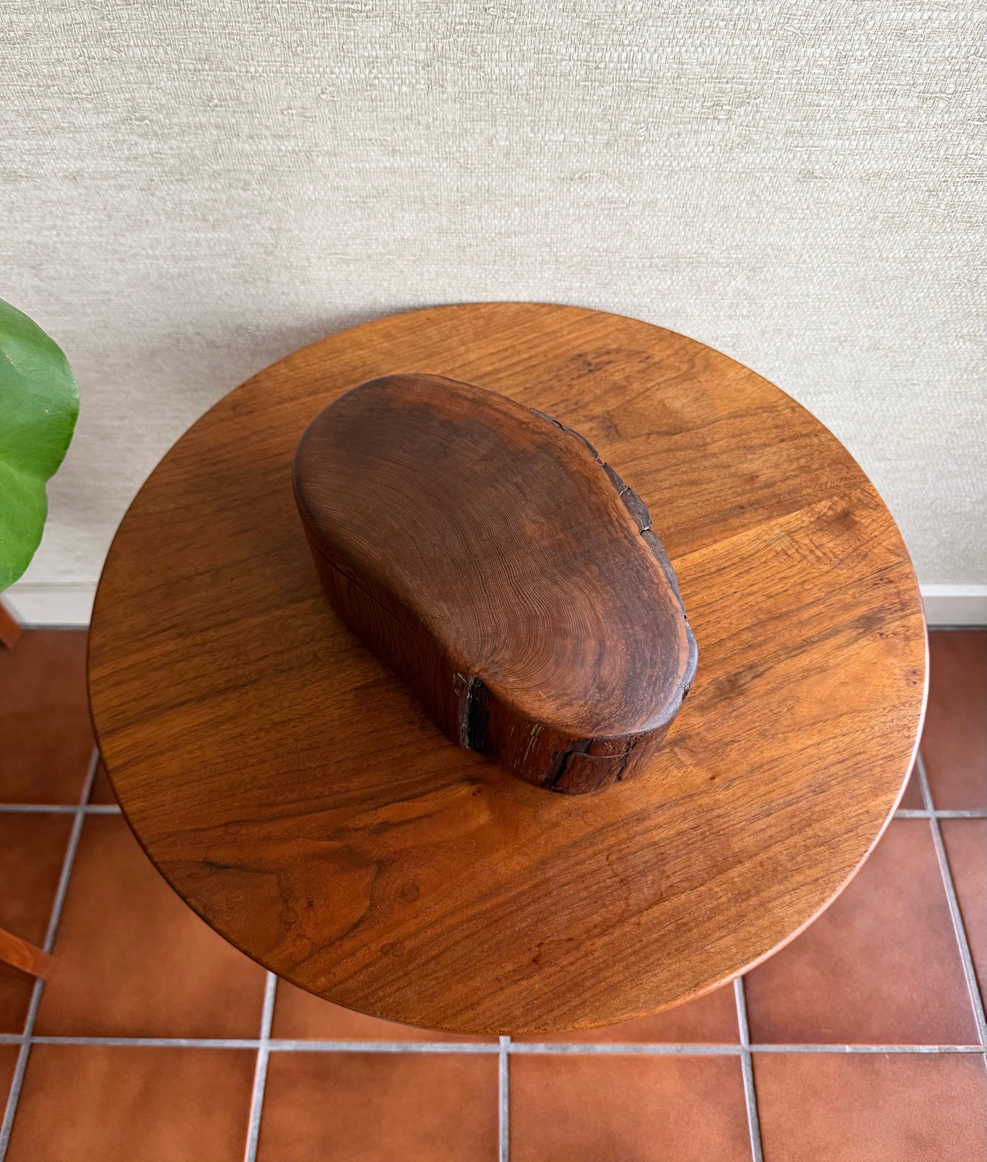 Wooden table with a large wooden box on top against a textured wall.